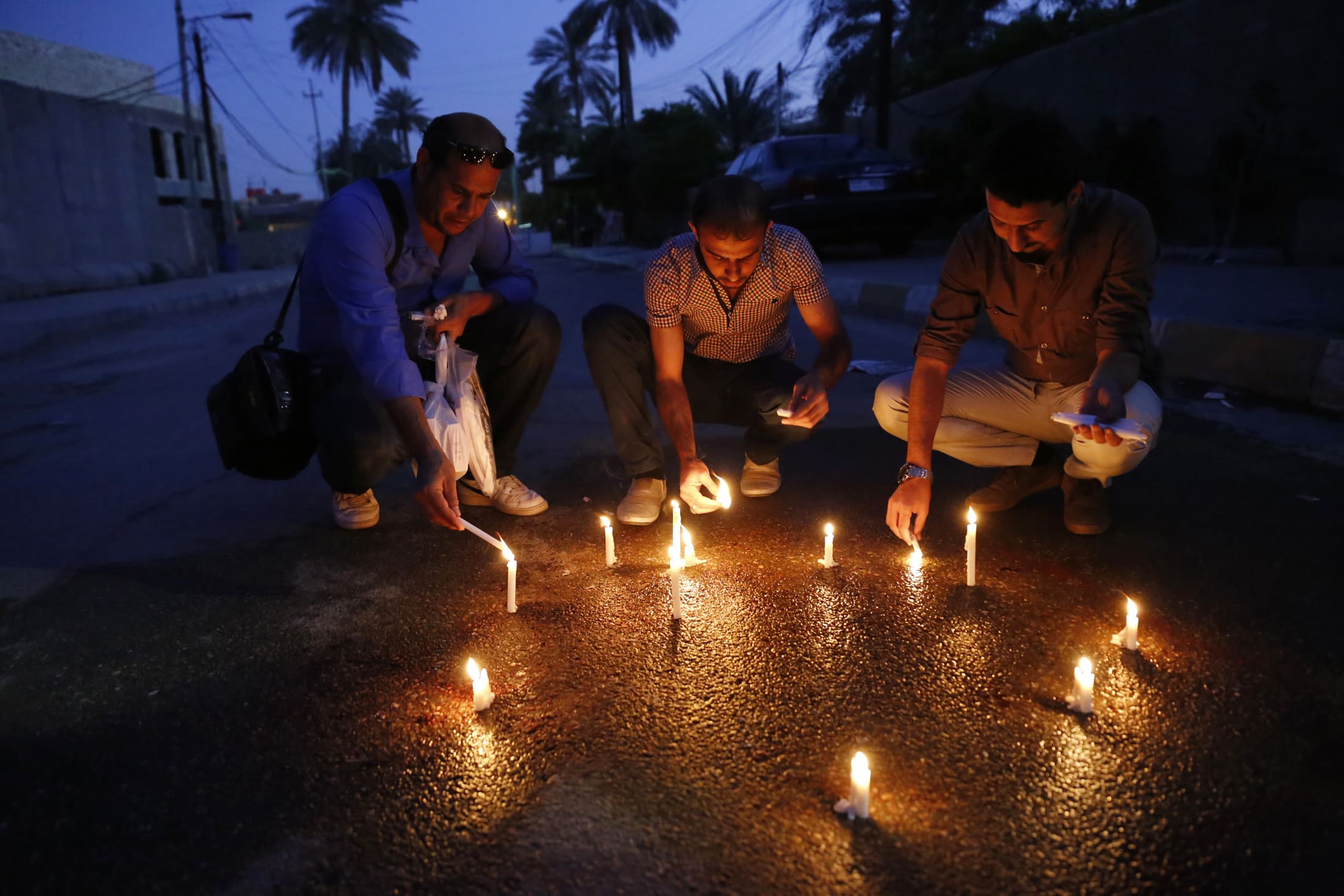 Iraqi journalists light candles at the site where Mohammed Badawi, the Baghdad bureau chief of Radio Free Iraq, was shot dead, 22 March 2014, REUTERS/Thaier al-Sudani