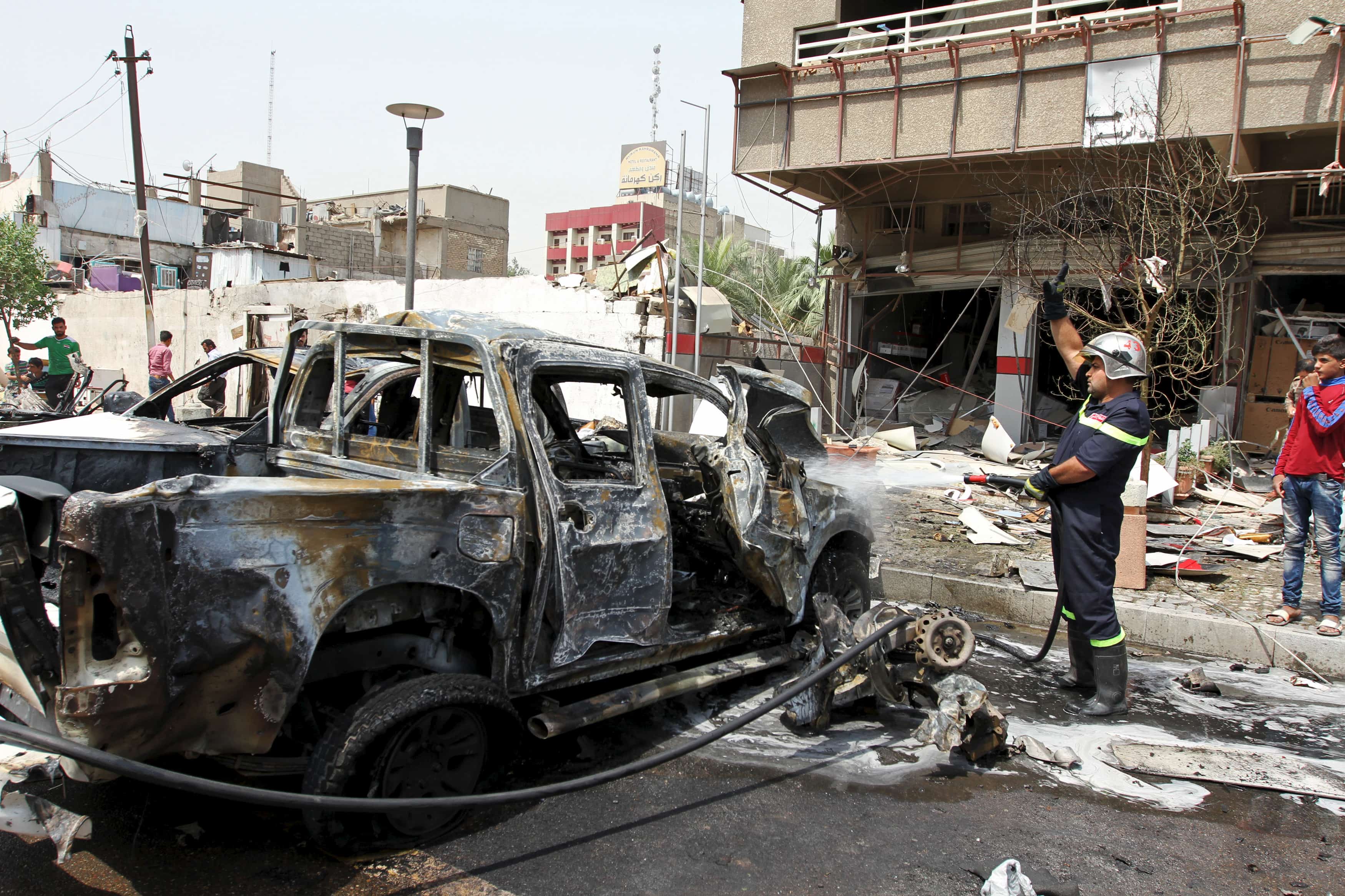 A fireman hoses down a burnt vehicle after a car bomb attack in Baghdad May 9, 2015., REUTERS/Stringer