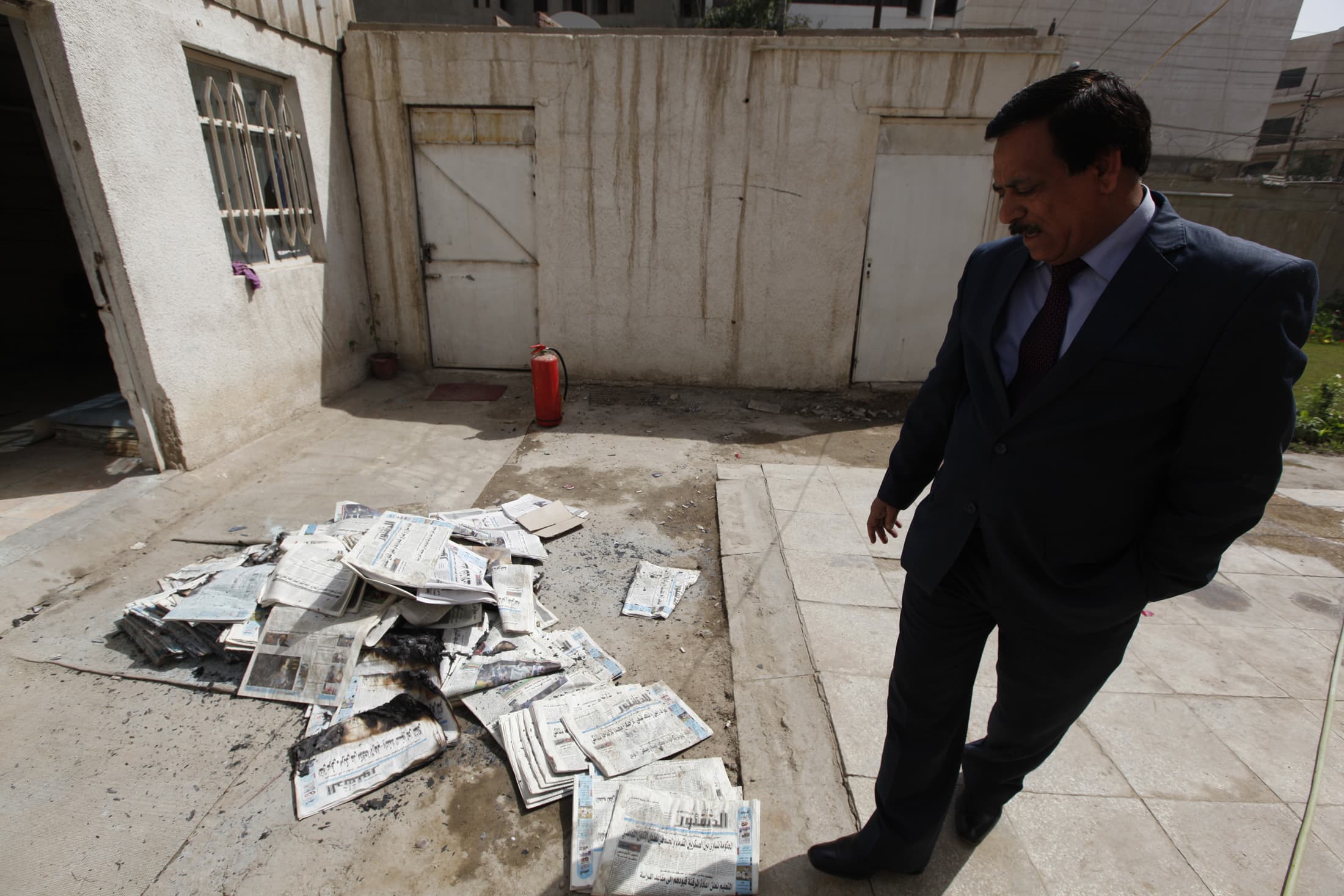 An Iraqi journalist walks past the archive newspapers burned after an attack by an armed group at Addustour newspaper's headquarters in Baghdad on 2 April 2013, REUTERS/Thaier al-Sudani