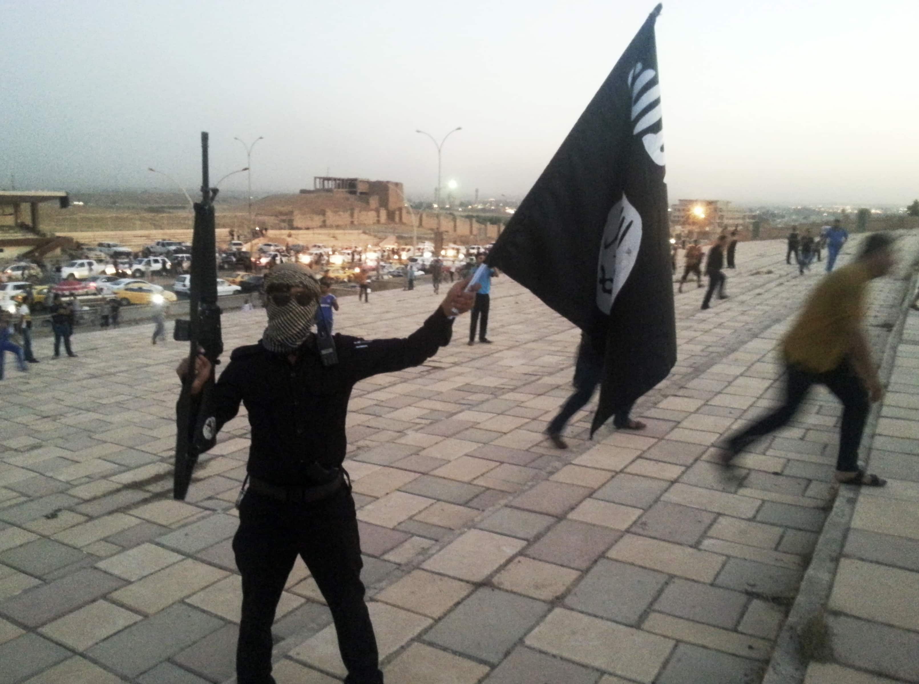 A fighter of the Islamic State of Iraq and Syria (ISIS) holds an ISIS flag and a weapon on a street in the city of Mosul, June 23, 2014,  REUTERS/Stringer