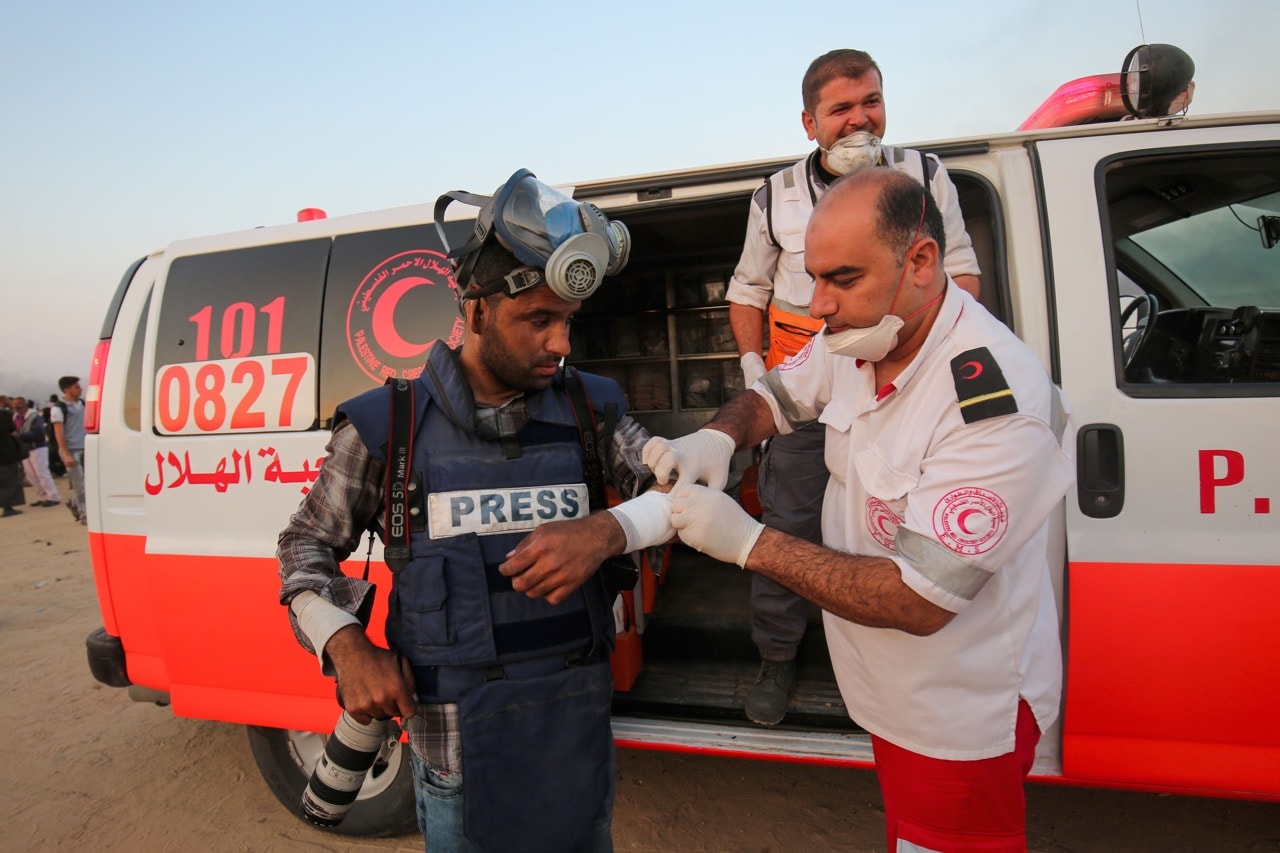 A Palestinian Red Crescent paramedic tends to an injured photojournalist during a demonstration near the border with Israel east of Khan Yunis in the southern Gaza Strip, 15 May 2018, SAID KHATIB/AFP/Getty Images