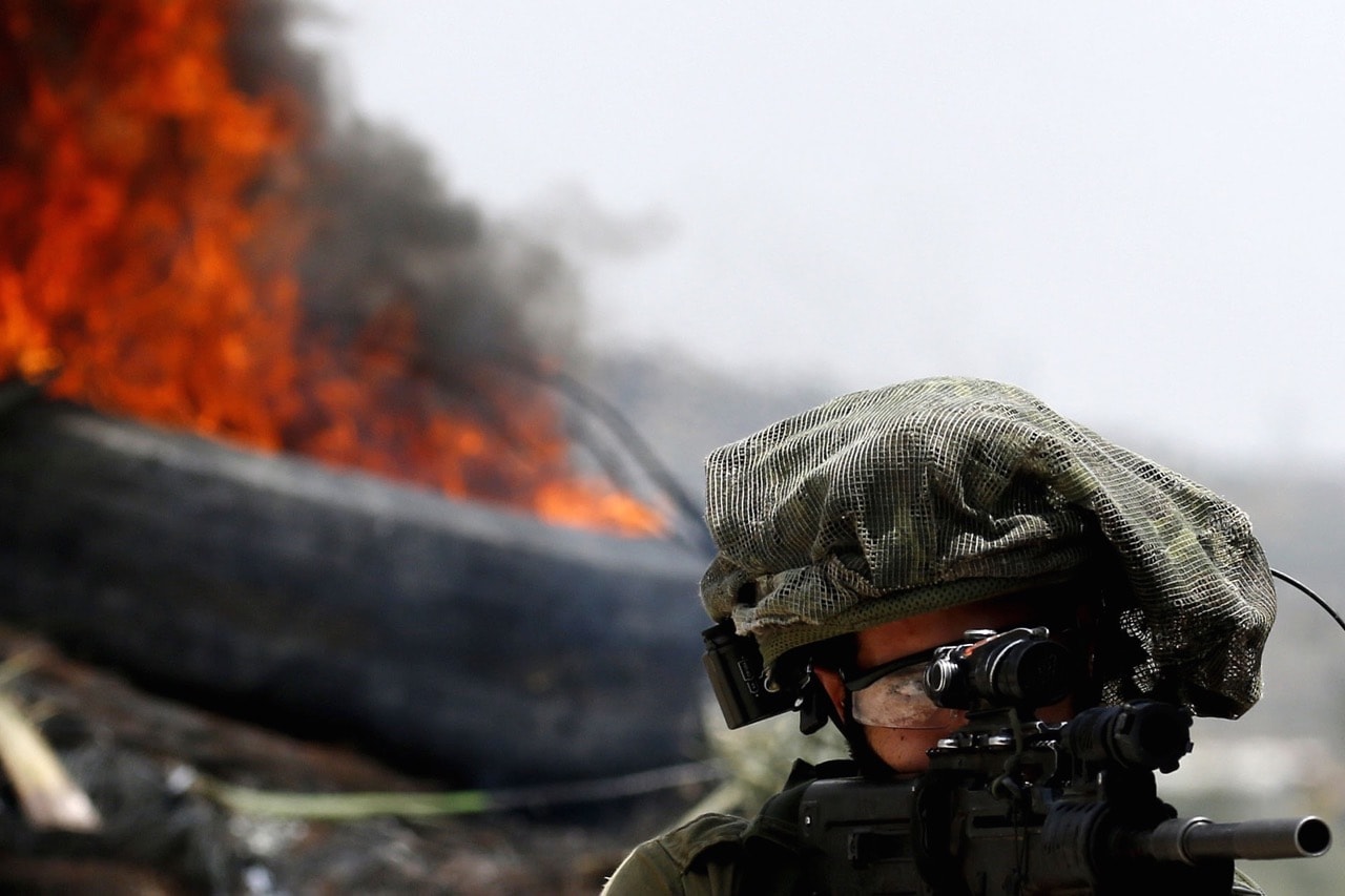 An Israeli soldier aims his weapon at Palestinian protesters during a weekly demonstration against the expropriation of Palestinian land by Israel in the village of Kfar Qaddum, in the occupied West Bank, 1 June 2018, JAAFAR ASHTIYEH/AFP/Getty Images