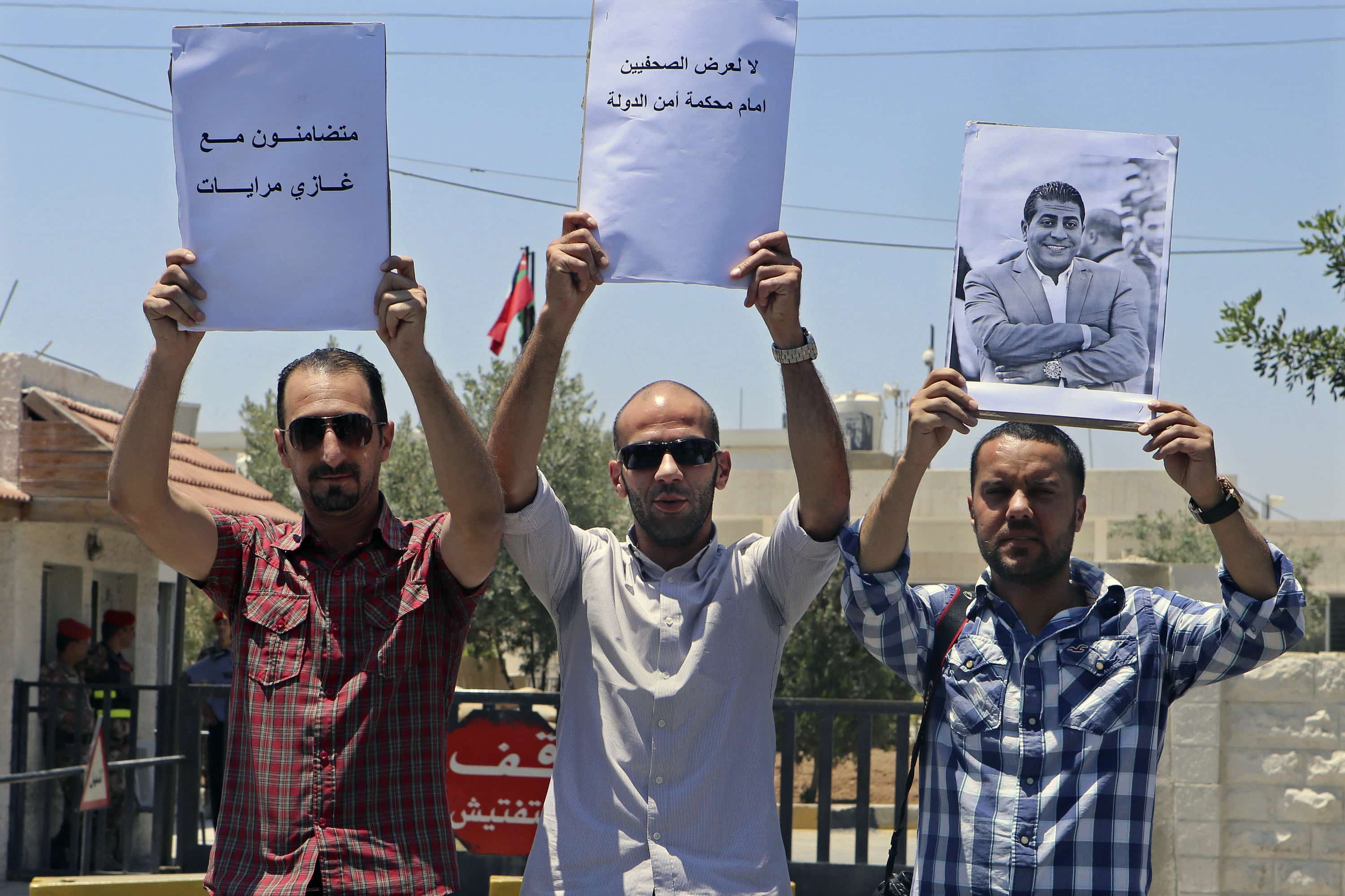 Jordanian Journalists hold a photo of their colleague Ghazi Mrayat and slogans as they gather outside the State Security Court calling for his release, in Amman,  July 11, 2015, AP Photo/Raad Adayleh