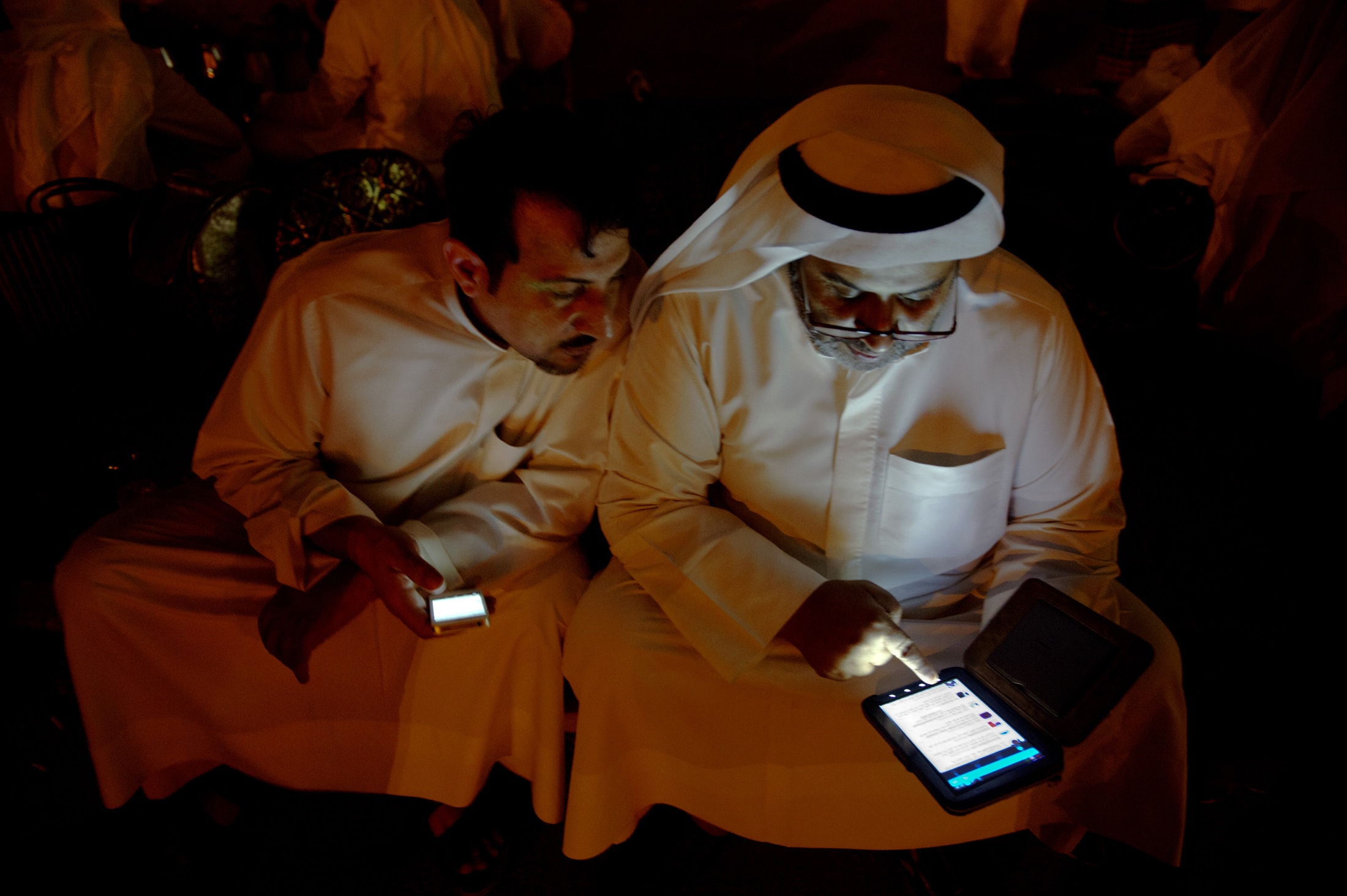 Kuwaiti citizen Raken Subaiya checks his Twitter feed on his phone as Yousef al Anazi looks on during a sit-in protest in front of the Justice Palace in Kuwait City October 19, 2012, REUTERS/Stephanie Mcgehee