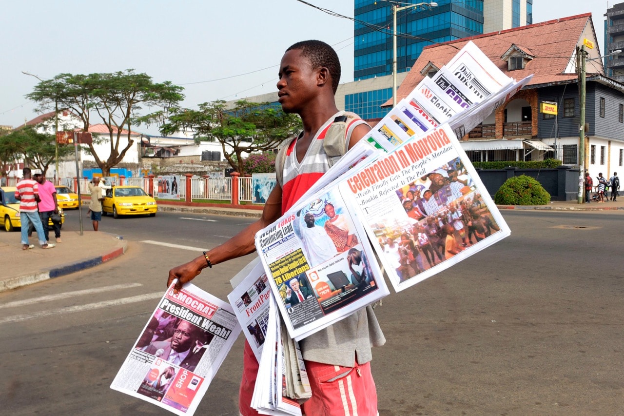 A man sells newspapers with headlines featuring the recent presidential elections on a roadside in Monrovia, Liberia, 29 December 2017, SEYLLOU/AFP/Getty Images