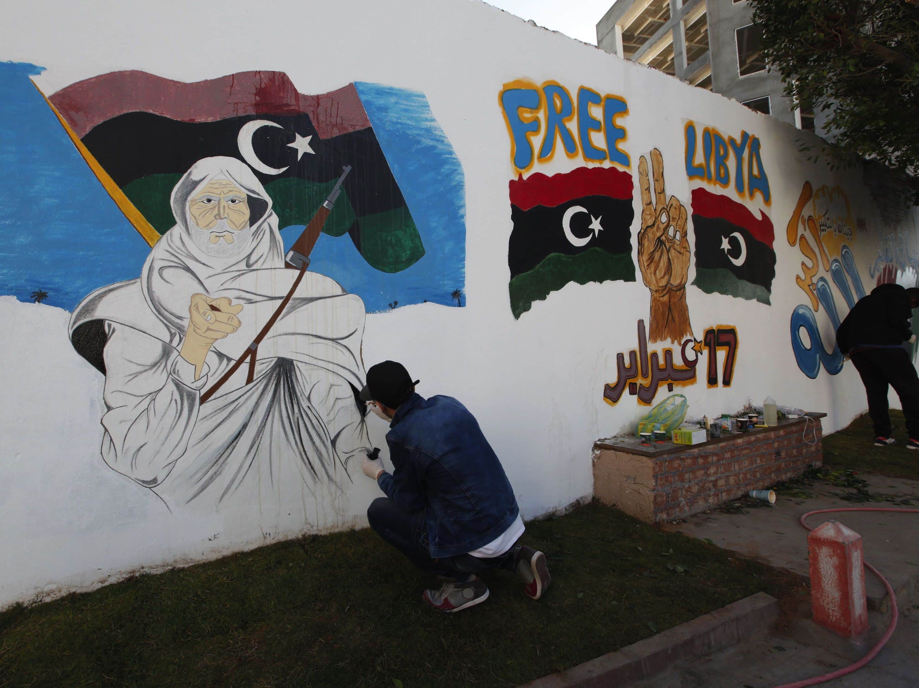 Libyans draw graffiti on a wall along a street in the capital Tripoli in preparation for celebrations of the third anniversary of the February 17 revolution, REUTERS/Ismail Zitouny