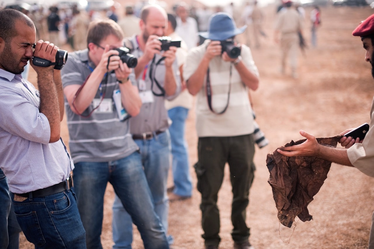 Photojournalists take pictures as a Libyan National Transitional Council (NTC) official shows them a scrap of a prison uniform found at Tripoli's notorious Abu Salim prison, 25 September 2011, LEON NEAL/AFP/Getty Images