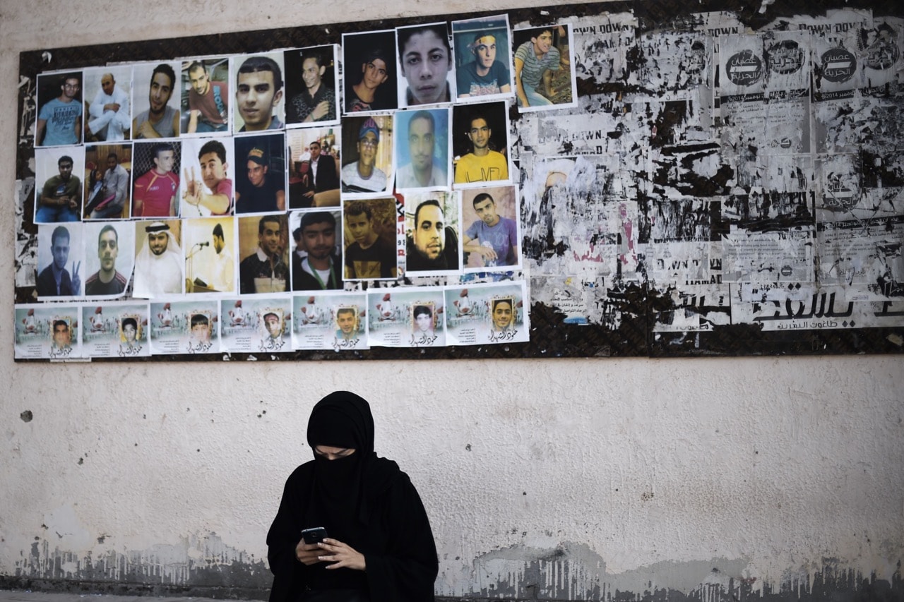 A Bahraini woman sits near portraits of jailed political activists, in the village of Sitra, 12 February 2016, MOHAMMED AL-SHAIKH/AFP/Getty Images