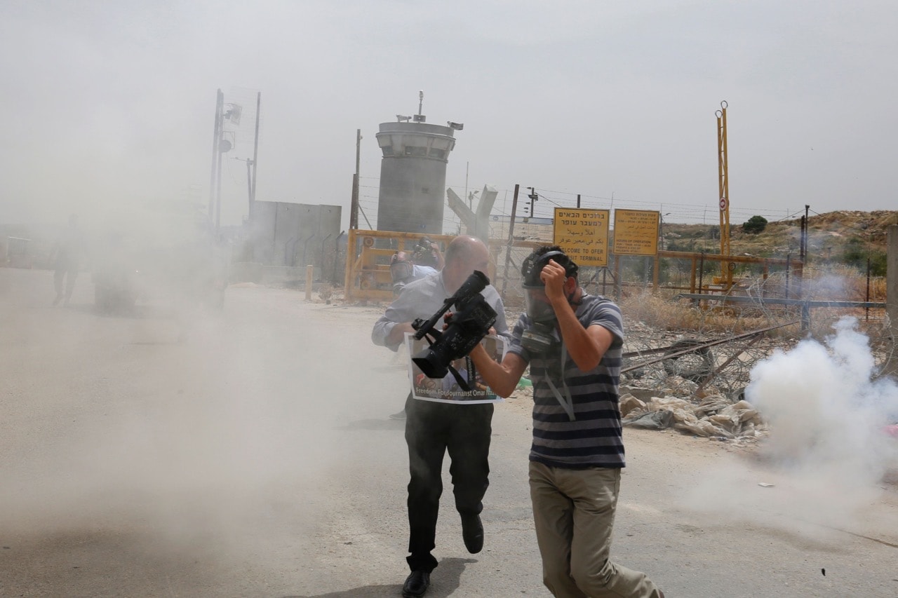 Palestinian journalists run for cover from tear gas canisters fired by Israeli forces during a demonstration on World Press Freedom day near Betunia in the West Bank, 3 May 2016, ABBAS MOMANI/AFP/Getty Images