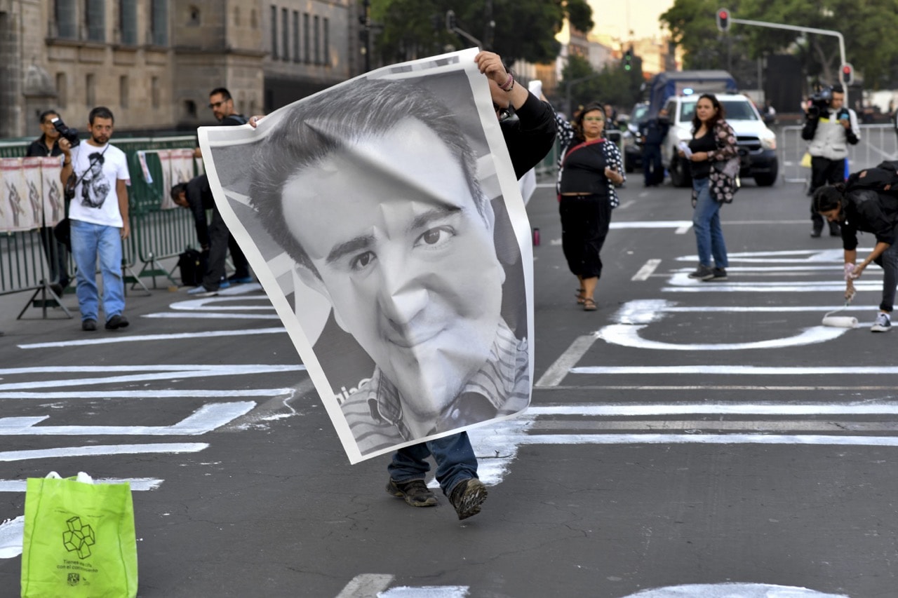 A journalist displays a poster with the image of one of the more than 140 journalists and photojournalists who were murdered and went missing in Mexico since 2000, during a protest in Mexico City, 1 June 2018, YURI CORTEZ/AFP/Getty Images