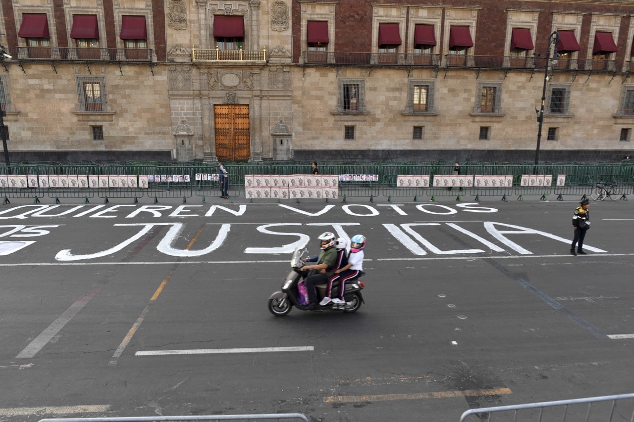 A police officer stands guard after members of the press wrote messages on the street during a protest against the murder or disappearance of more than 140 journalists in Mexico since 2000, in front of the National Palace in Mexico City, 1 June 2018, YURI CORTEZ/AFP/Getty Images