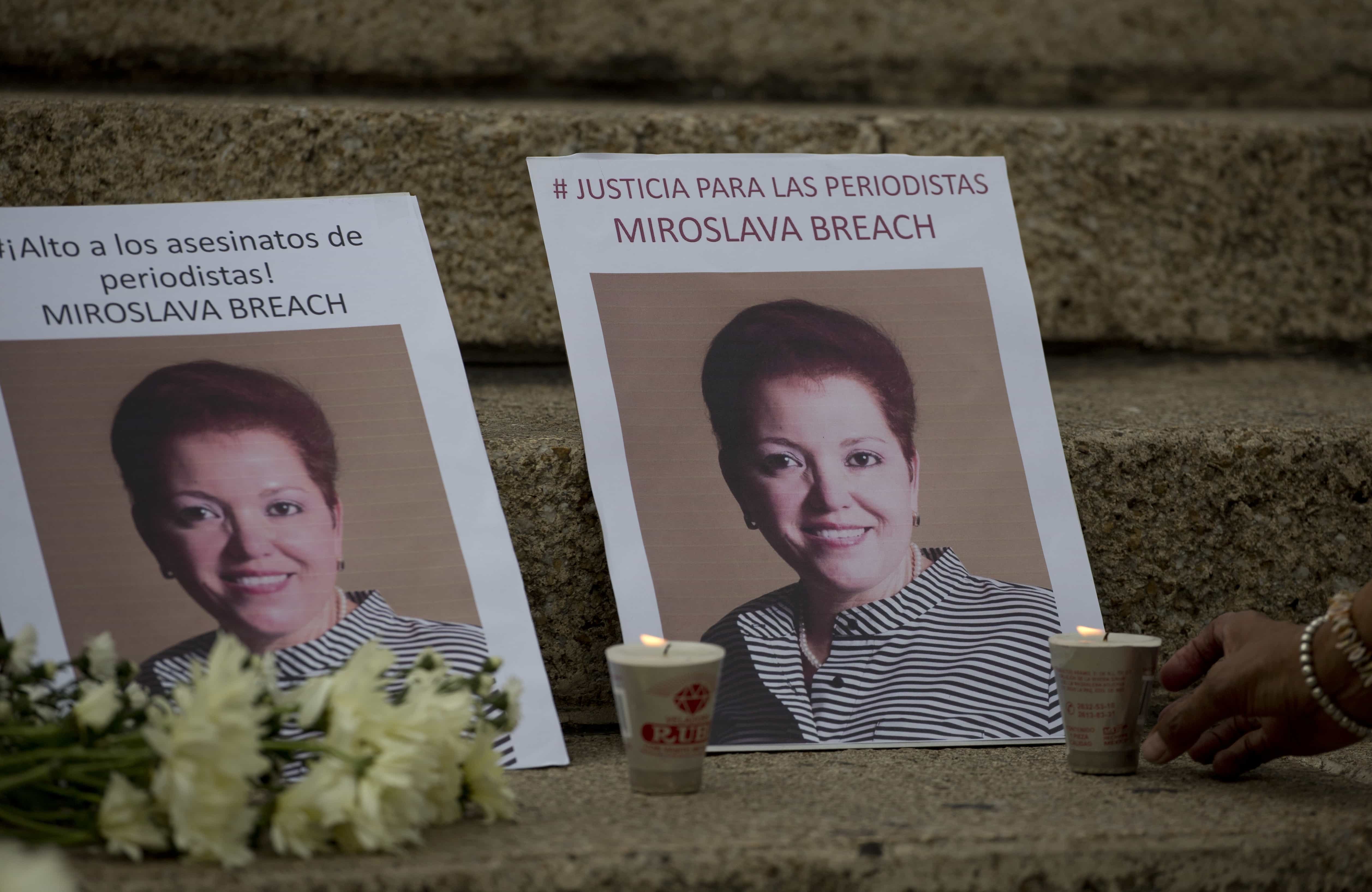 A woman lights a candle beside photos of Mexican journalist, Miroslava Breach, AP Photo/Eduardo Verdugo