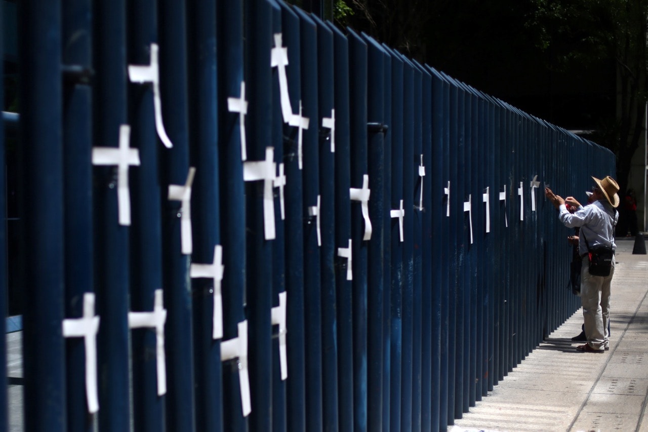 An activist puts crosses on a fence as he protests against the murder of journalists in Mexico, outside the Attorney General's Office (PGR) in Mexico City, 1 April 2017, REUTERS/Edgard Garrido