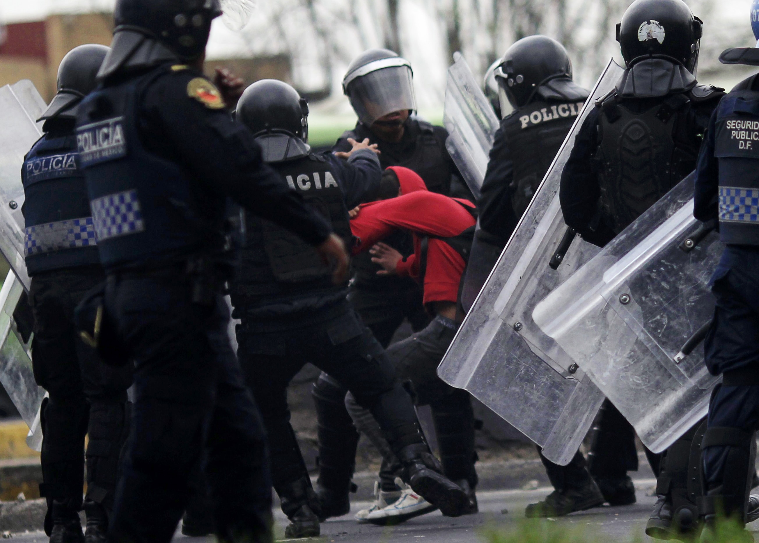 Riot police grab a demonstrator during a protest over the 43 missing Ayotzinapa students, near the airport in Mexico City, REUTERS/Carlos Jasso