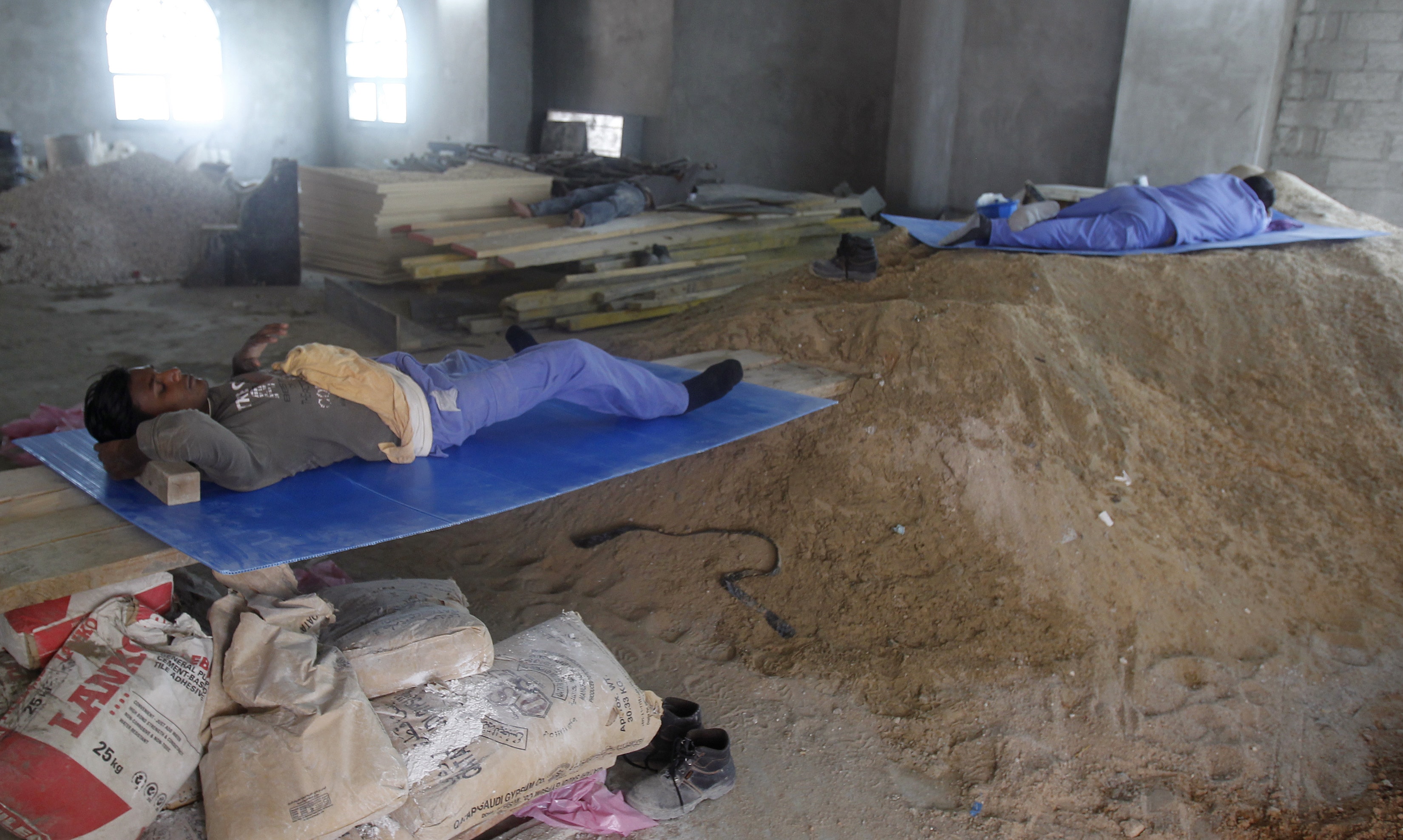 Construction workers rest during their lunch break in Doha June 18, 2012, REUTERS/Stringer