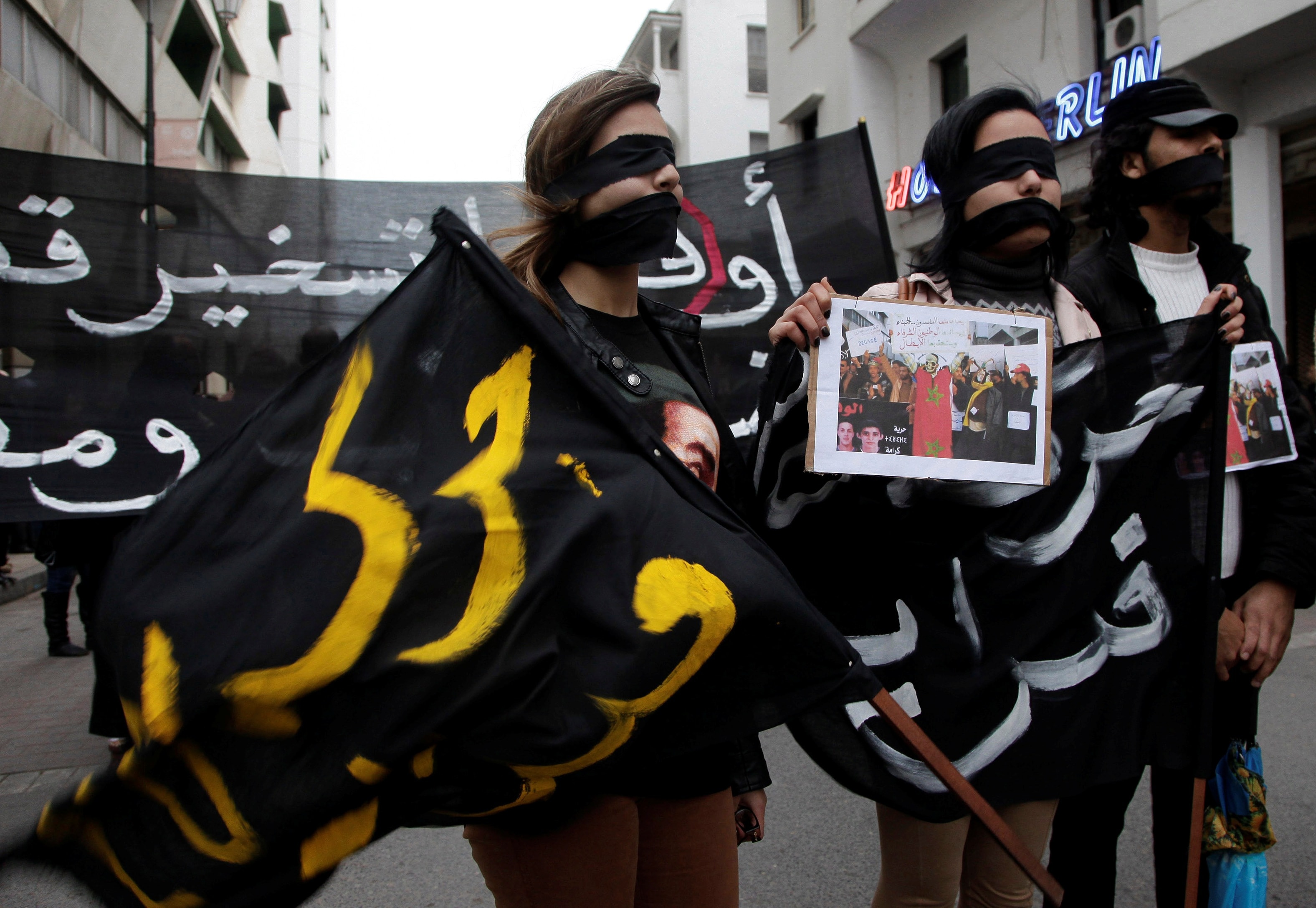 Moroccan "February 20" movement activists cover their eyes and hold a flag that reads "February 20 movement" as they take part in a demonstration demanding the release of political prisoners in Rabat on 20 January 2013, REUTERS/Stringer