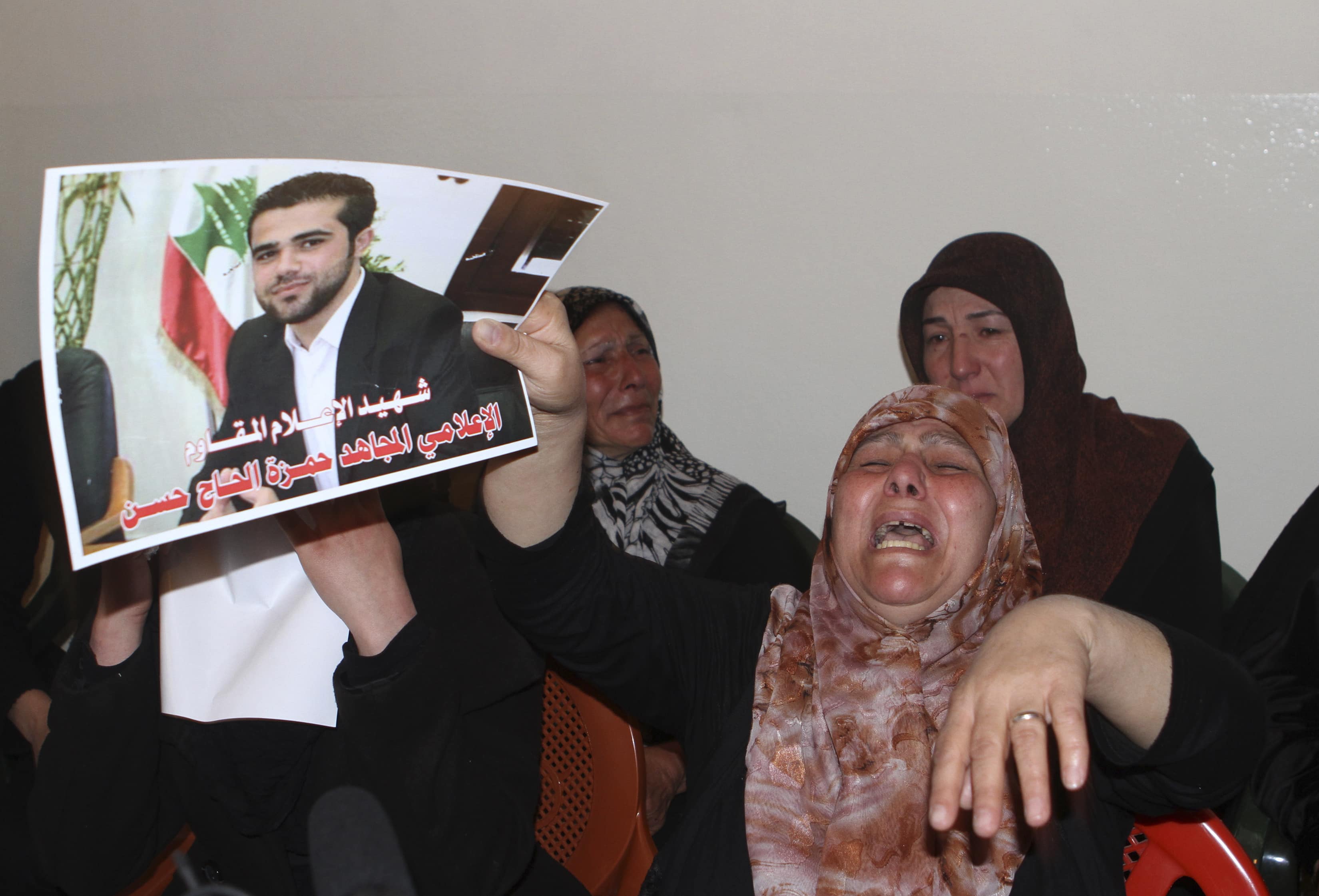 Mother of Hamza Haj Hassan, a reporter for Hezbollah's al-Manar television, holds his picture as she mourns his death in his home village in Shaath on 15 April 2014, REUTERS/Ahmad Shalha
