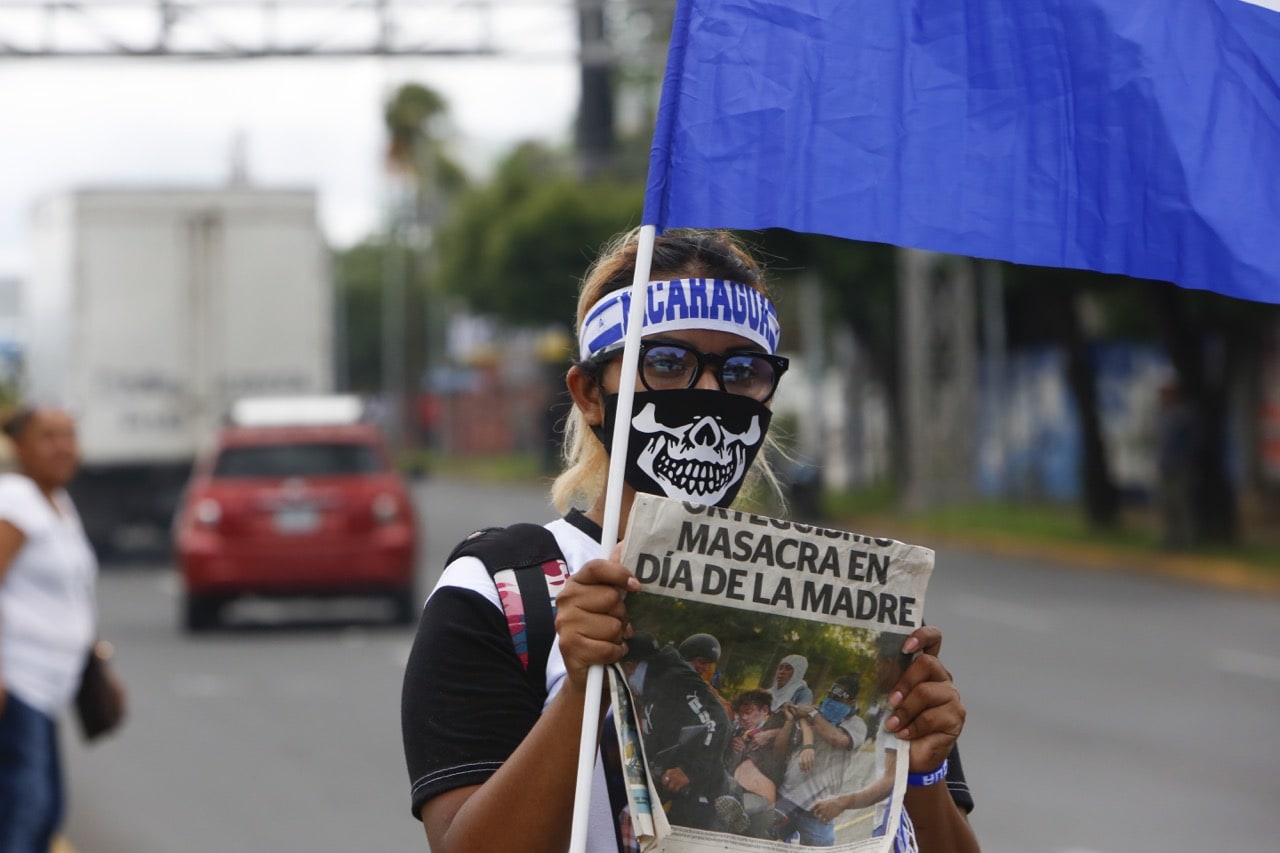 A masked protester shows the cover of a local newspaper with the headline "Massacre on Mother's Day", in Managua, Nicaragua, 4 July 2018, Stringer/Anadolu Agency/Getty Images