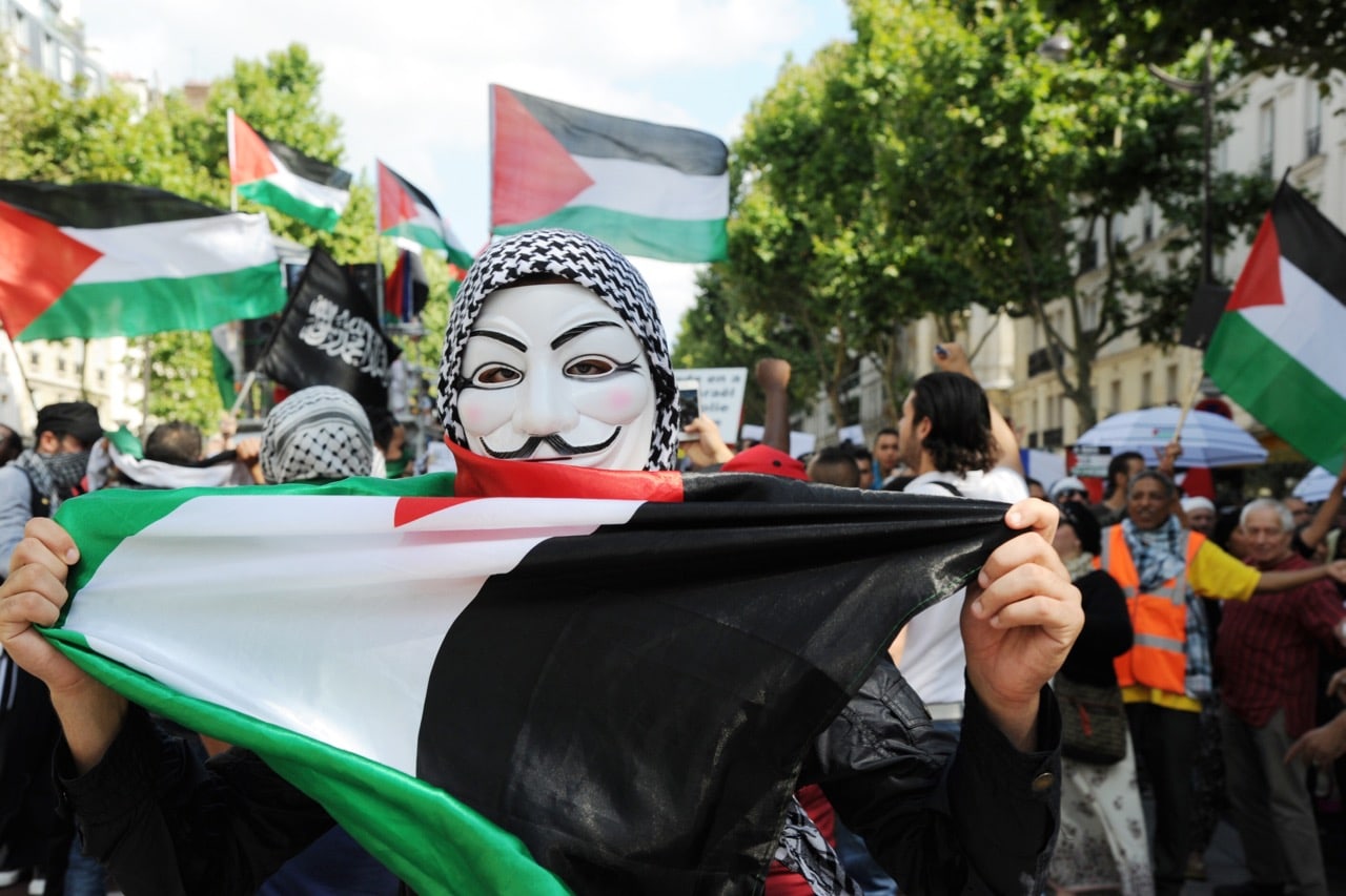 A protester wearing a mask of the Anonymous computer hacking activists group and holding the Palestinian flag takes part in a demonstration in Paris, France on 2 August 2014, DOMINIQUE FAGET/AFP/Getty Images