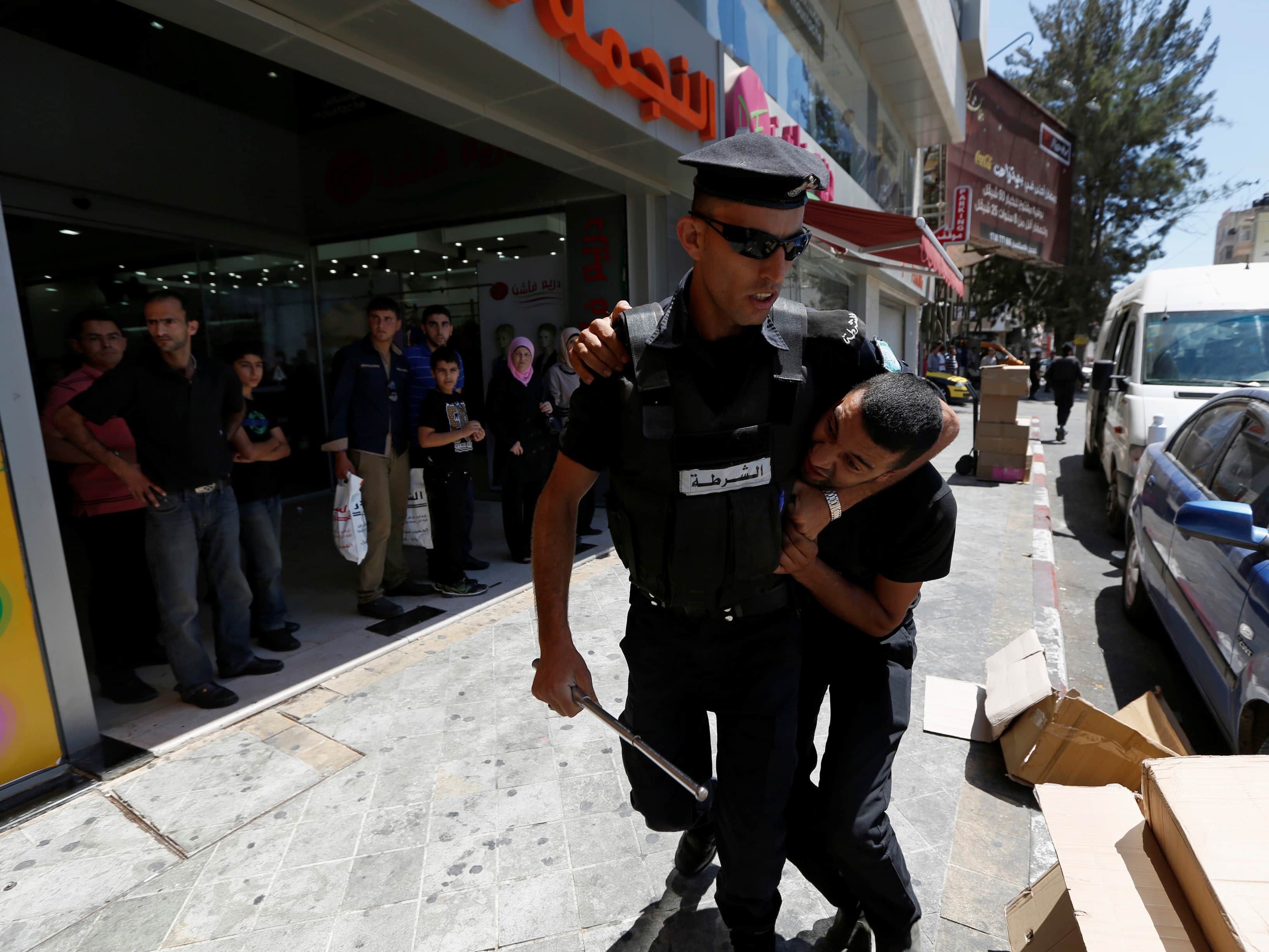 A Palestinian policeman detains a protester during a demonstration against the renewal of stalled peace talks with Israel, in the West Bank city of Ramallah, 28 July 2013, REUTERS/Mohamad Torokman