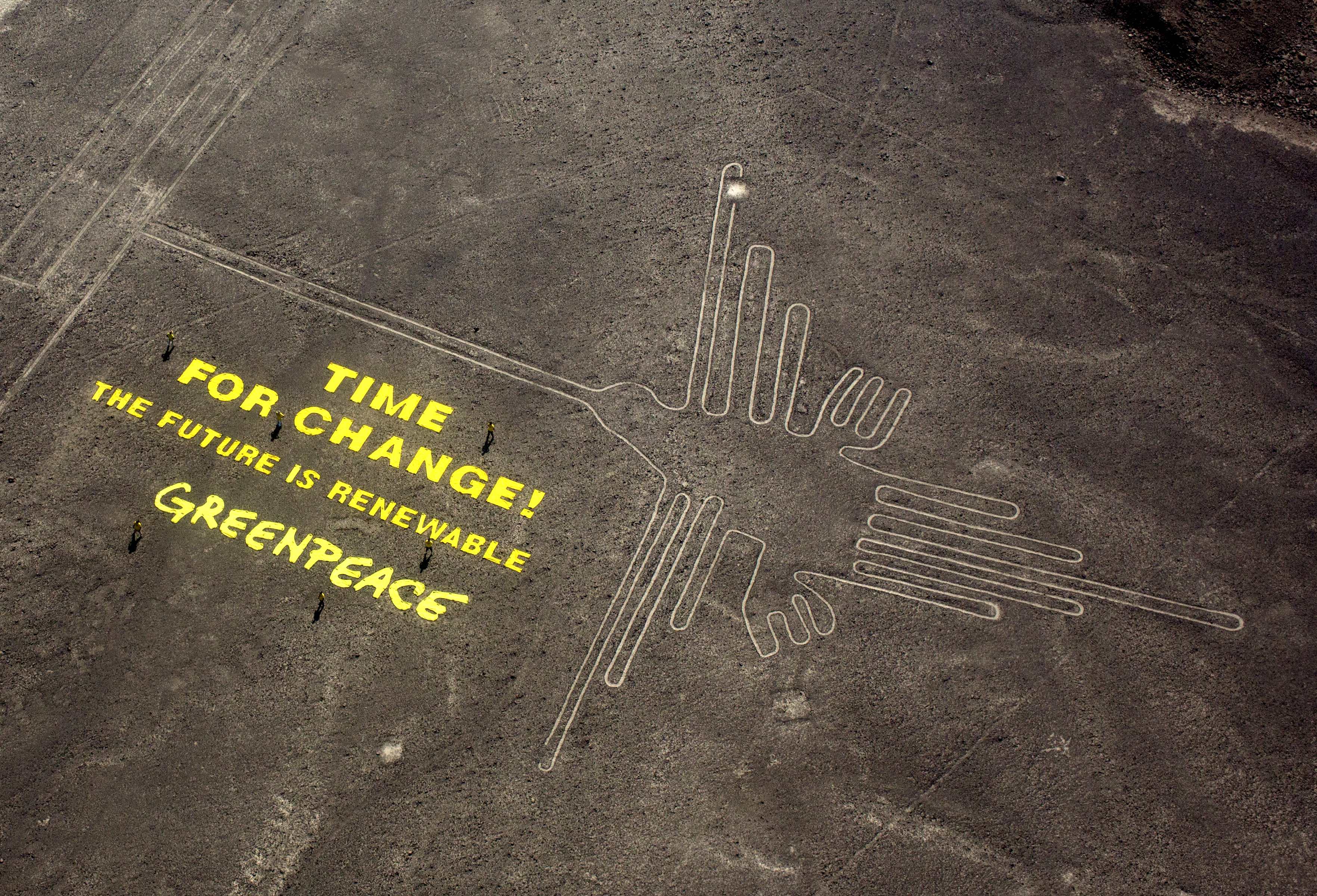 Greenpeace activists stand next to large letters that spell out "Time for Change: The Future is Renewable" next to the hummingbird geoglyph in Nazca, Peru, AP Photo/Rodrigo Abd, File