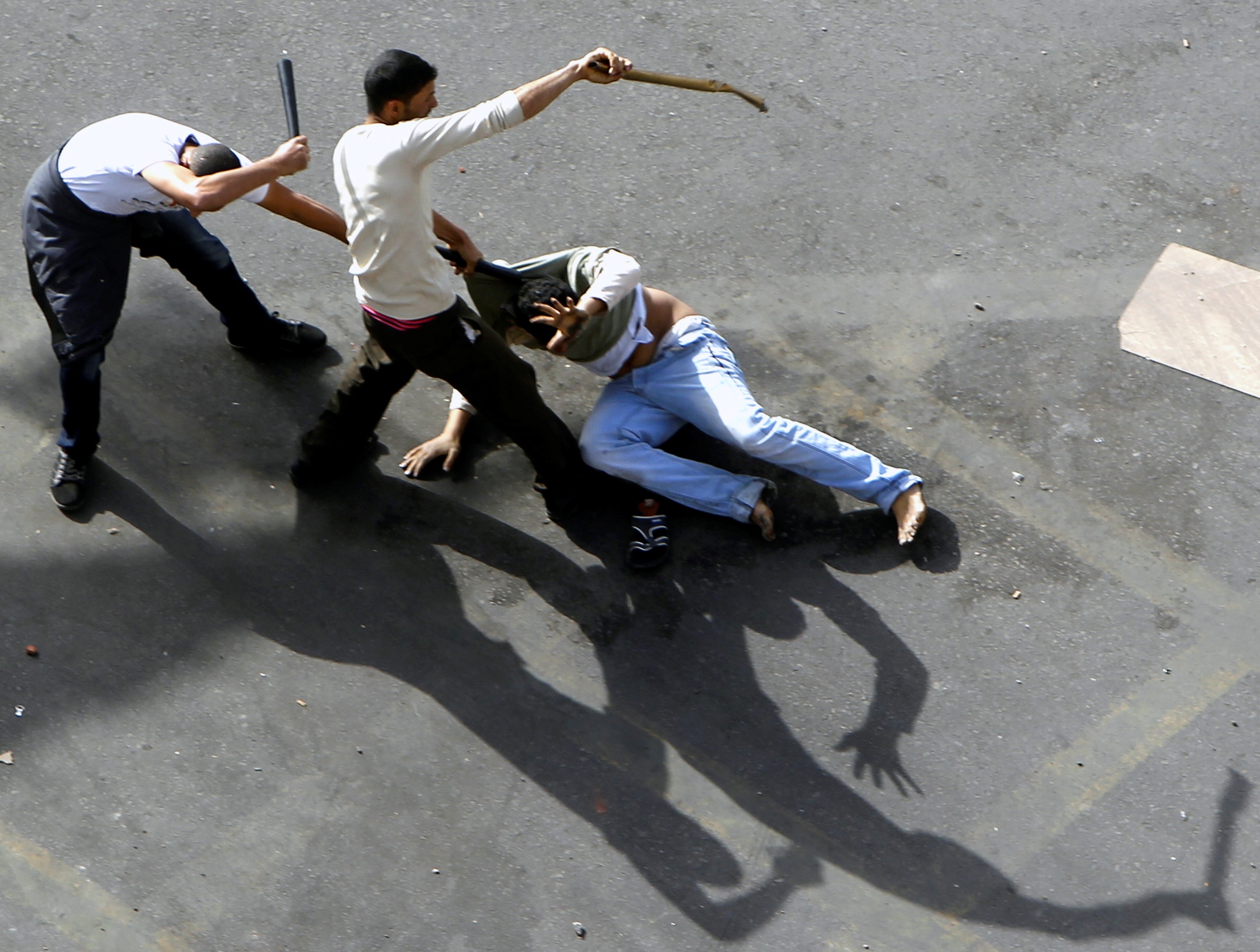 Plain-clothes security personnel beat an anti-government protester at Cairo's Tahrir Square on 3 March 2013, REUTERS/Mohamed Abd El Ghany