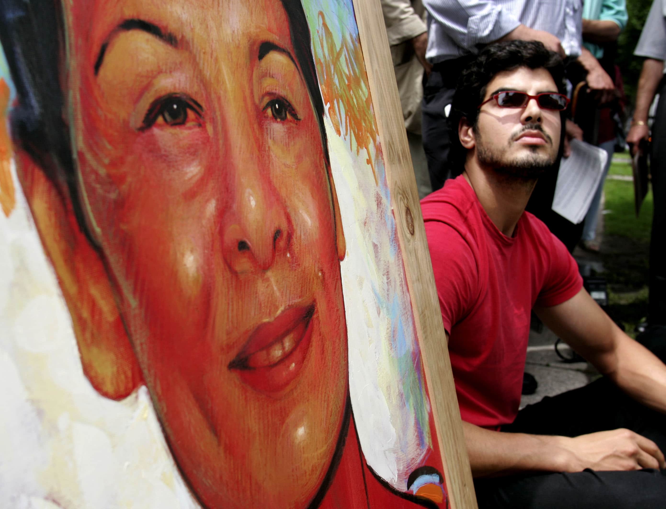 Stephan Hachemi, son of Zahra Kazemi, sits beside a portrait of his mother during a protest outside the Iranian Embassy in Ottawa in 2004, REUTERS/Jim Young JY/HB