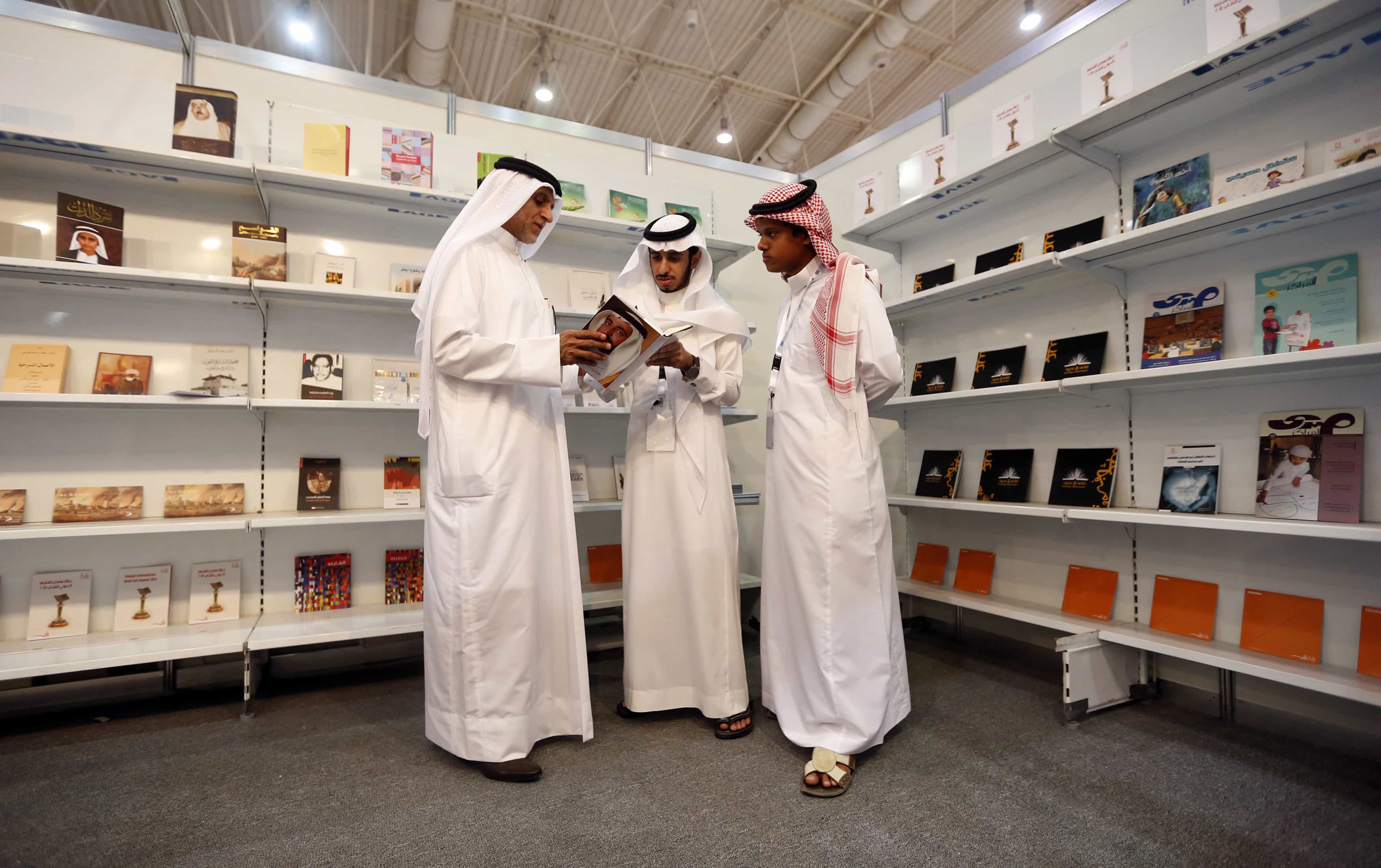 Men examine a book during a book fair in Riyadh on 5 March 2014, REUTERS/Faisal Al Nasser
