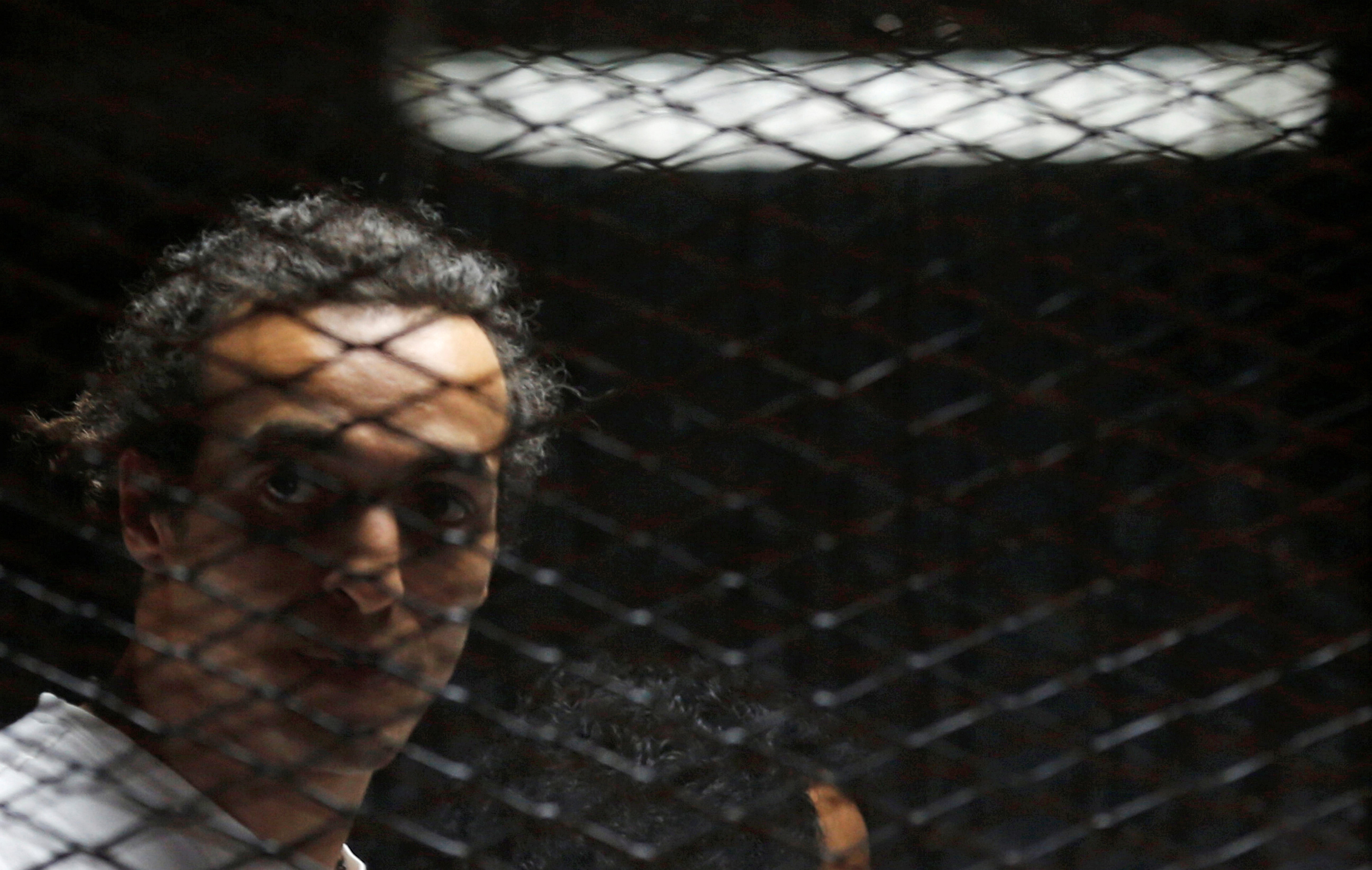 Egyptian photojournalist Mahmoud Abu Zeid, also known as "Shawkan", looks on behind bars in his trial at on the outskirts of Cairo, Egypt May 31, 2016. , REUTERS/Amr Abdallah Dalsh