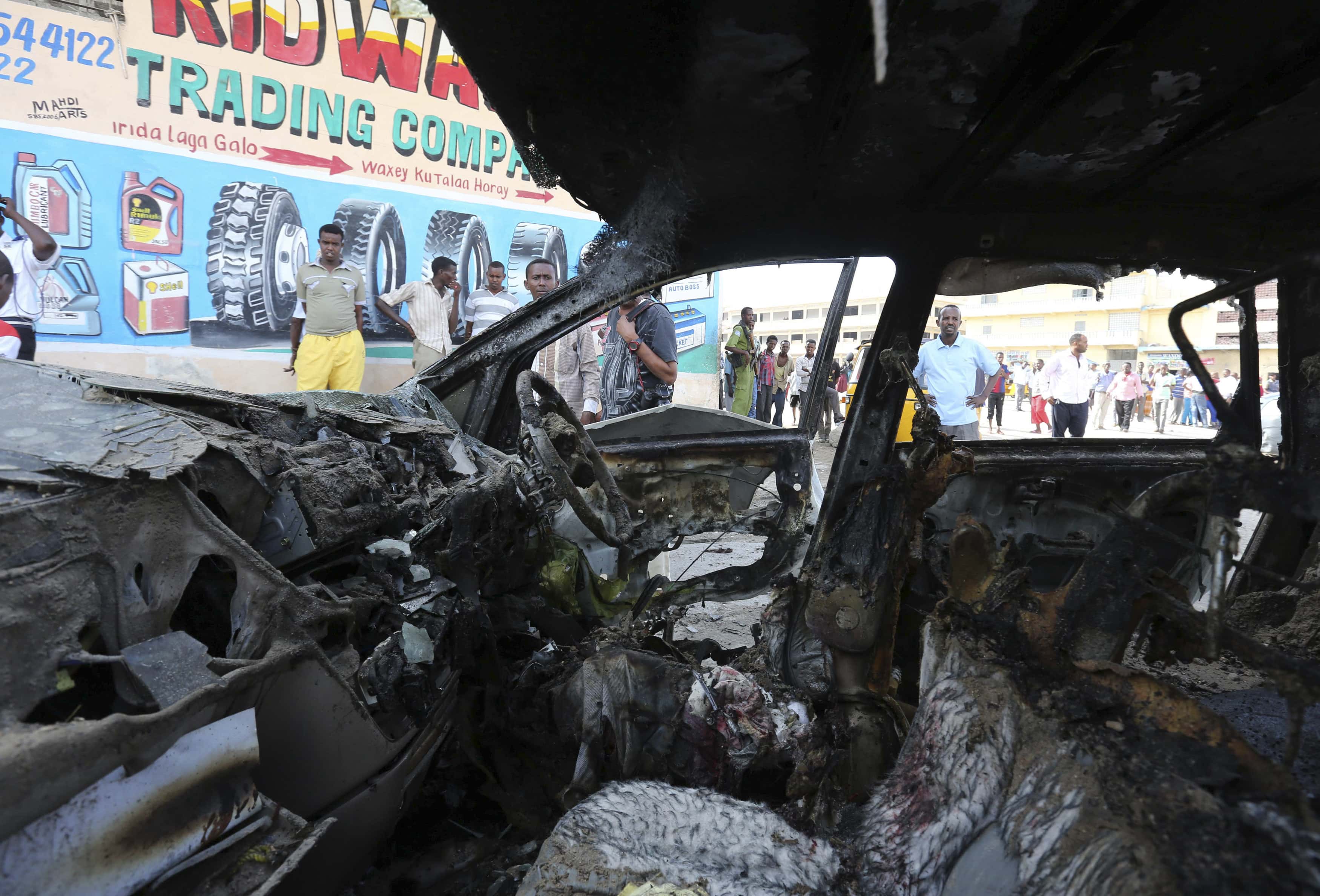 People look at the wreckage of a car at the scene of an explosion where local journalist Yusuf Keynan was killed in Somalia's capital Mogadishu, 21 June 2014, REUTERS/Feisal Omar