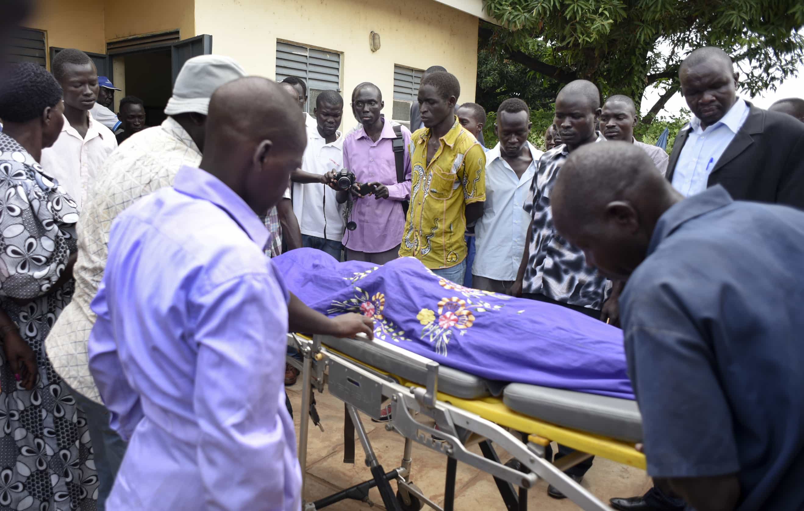 Mourners watch as the body of South Sudanese journalist Moi is taken into the mortuary in Juba, South Sudan, 20 August 2015, AP Photo/Jason Patinkin