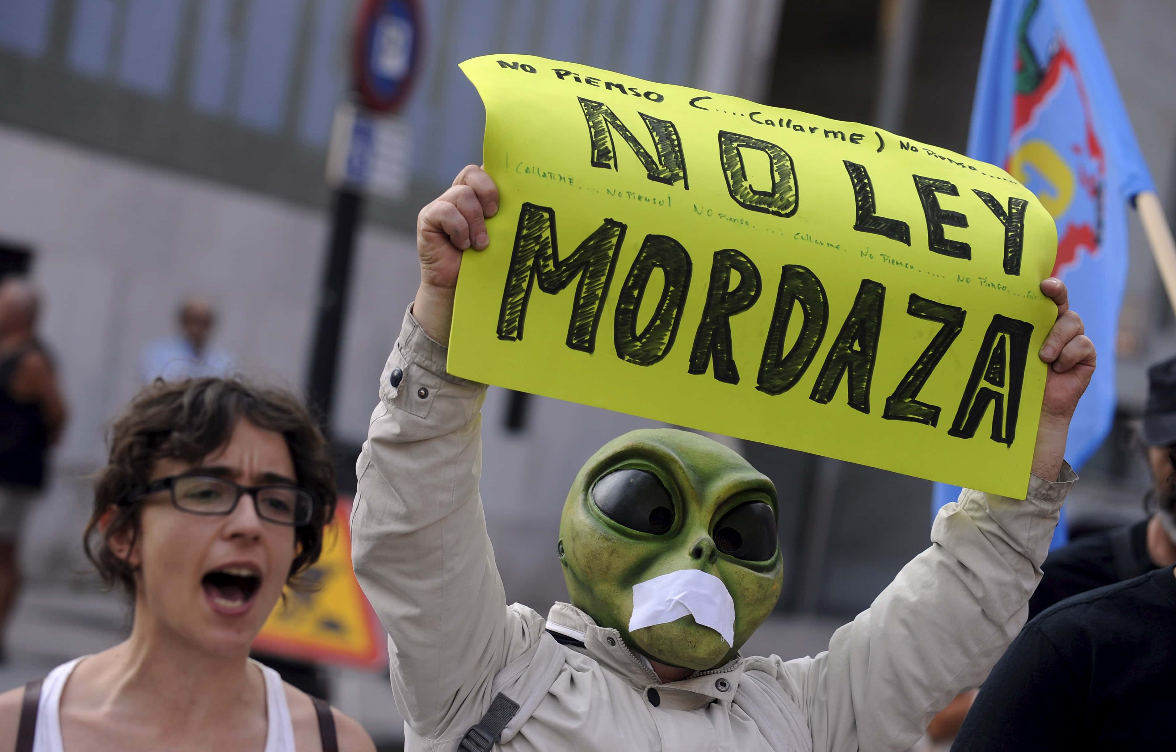 A man holds up a sign that reads "no to gag law" during a protest in Gijon, 30 June 2015, REUTERS/Eloy Alonso