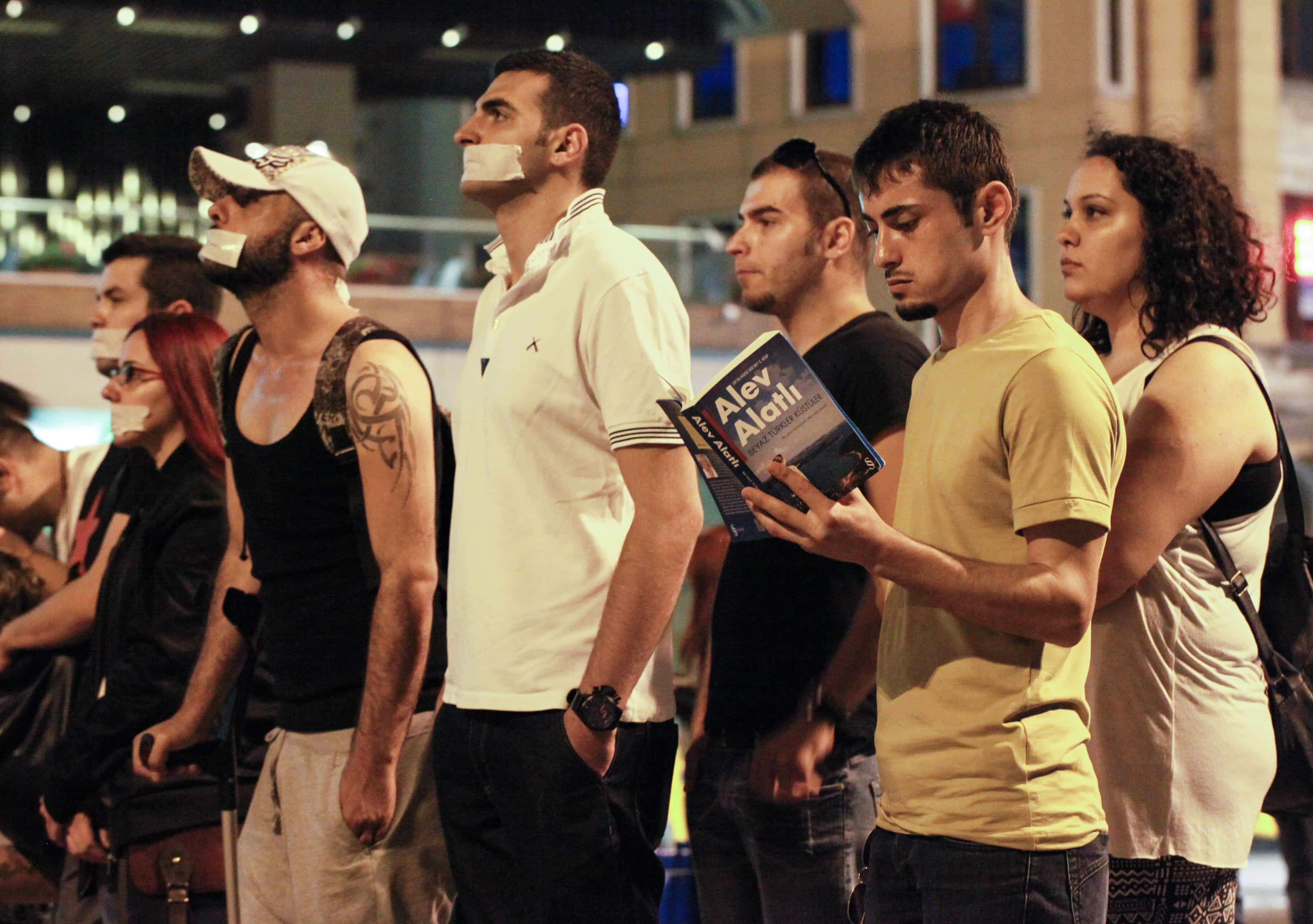 People standing in protest in Istanbul with a man reading a book by Alev Alatli, a writer who has experienced censorship in Turkey, on 18 June 2013., Miguel Crarminati/Demotix