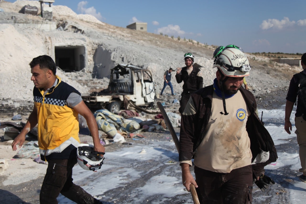 Syrian civil defence members search near a burned vehicle  after an airstrike by pro-regime forces, in Hass town, Idlib province, 8 September 2018, AMER ALHAMWE/AFP/Getty Images