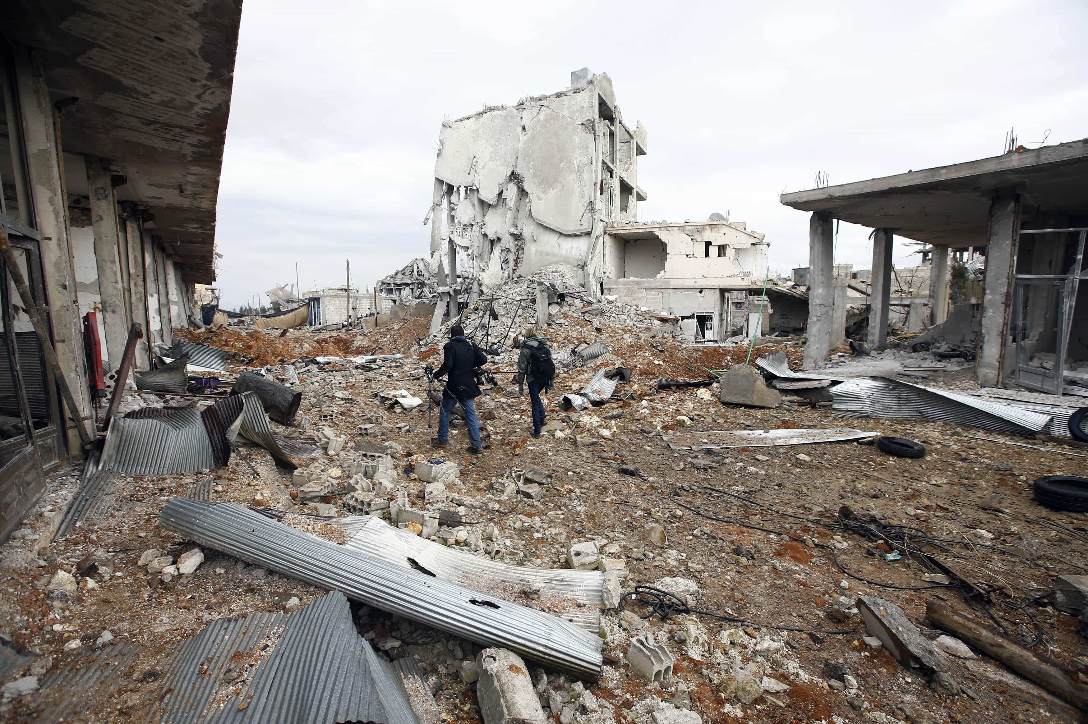 Visiting journalists walk between damaged buildings in the northern Syrian town of Kobani, 30 January 2015, REUTERS/Osman Orsal