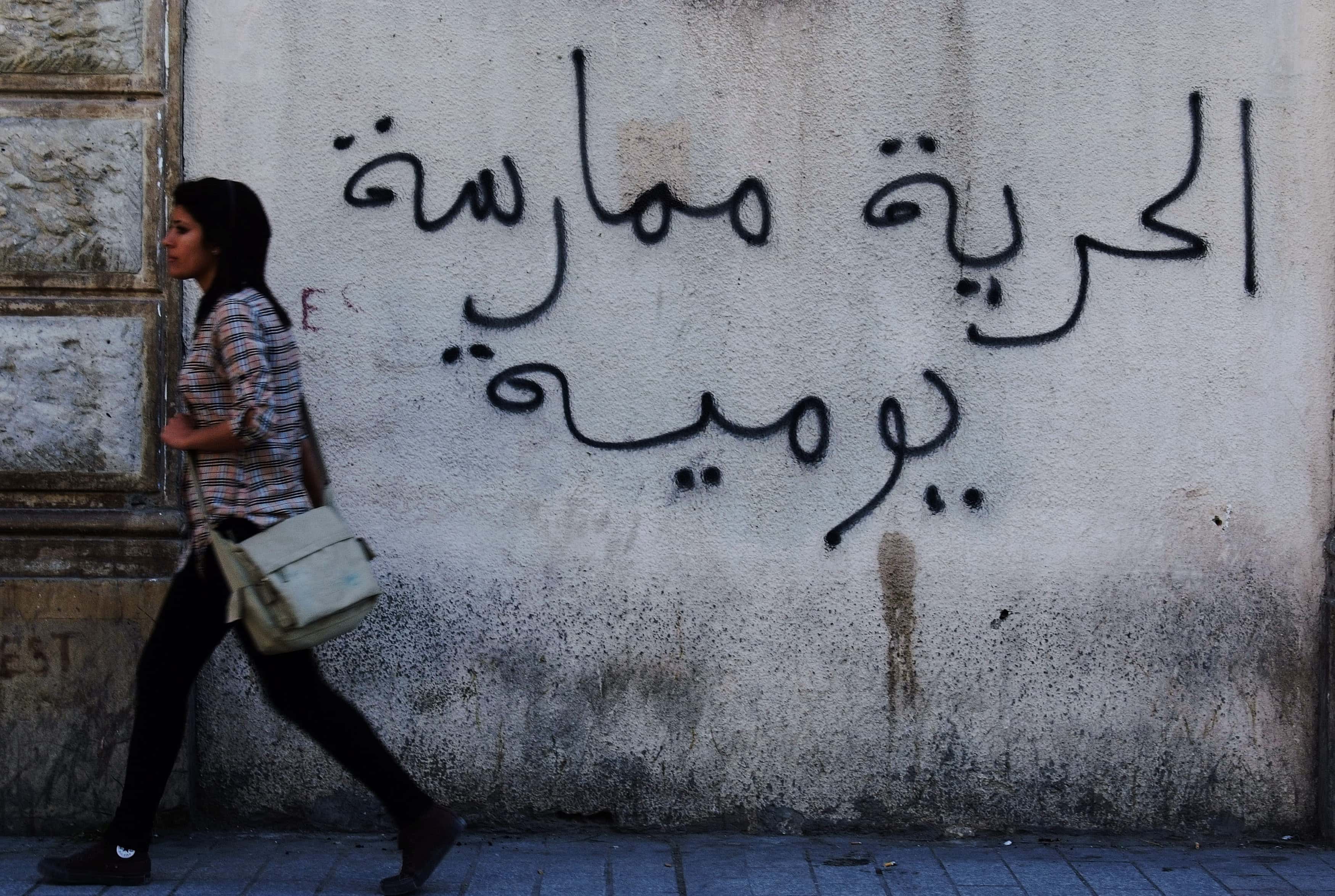 A Tunisian woman walks past graffiti which reads, "Freedom is a daily practice" in Tunis in 2011.   , REUTERS/Anis Mili