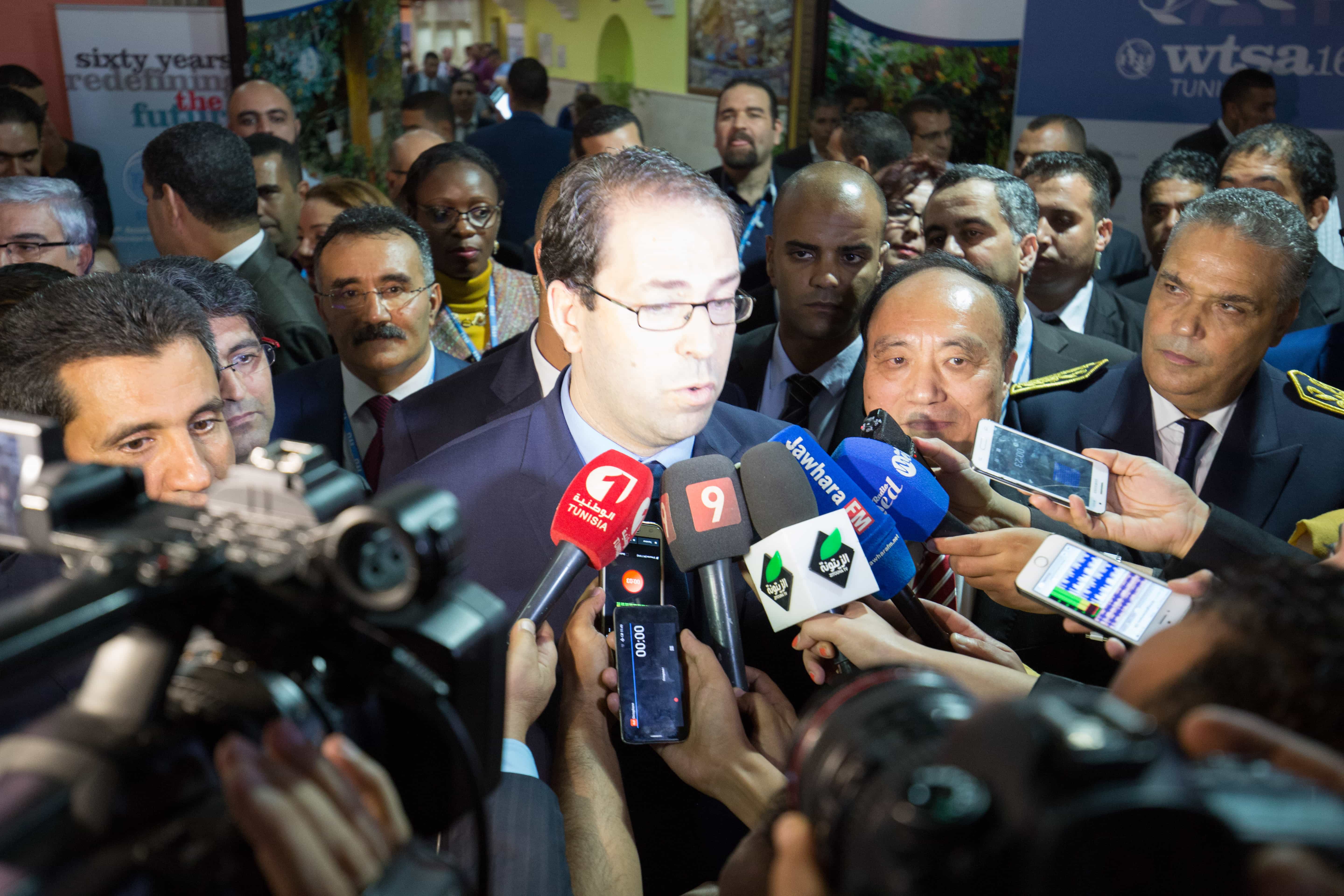 Tunisian Prime Minister Youssef Chahed speaking to the media during the 2016 World Telecommunication Standardization Assembly which took place in Tunisia, Photo by the ITU, shared on Flickr under a Creative Commons License