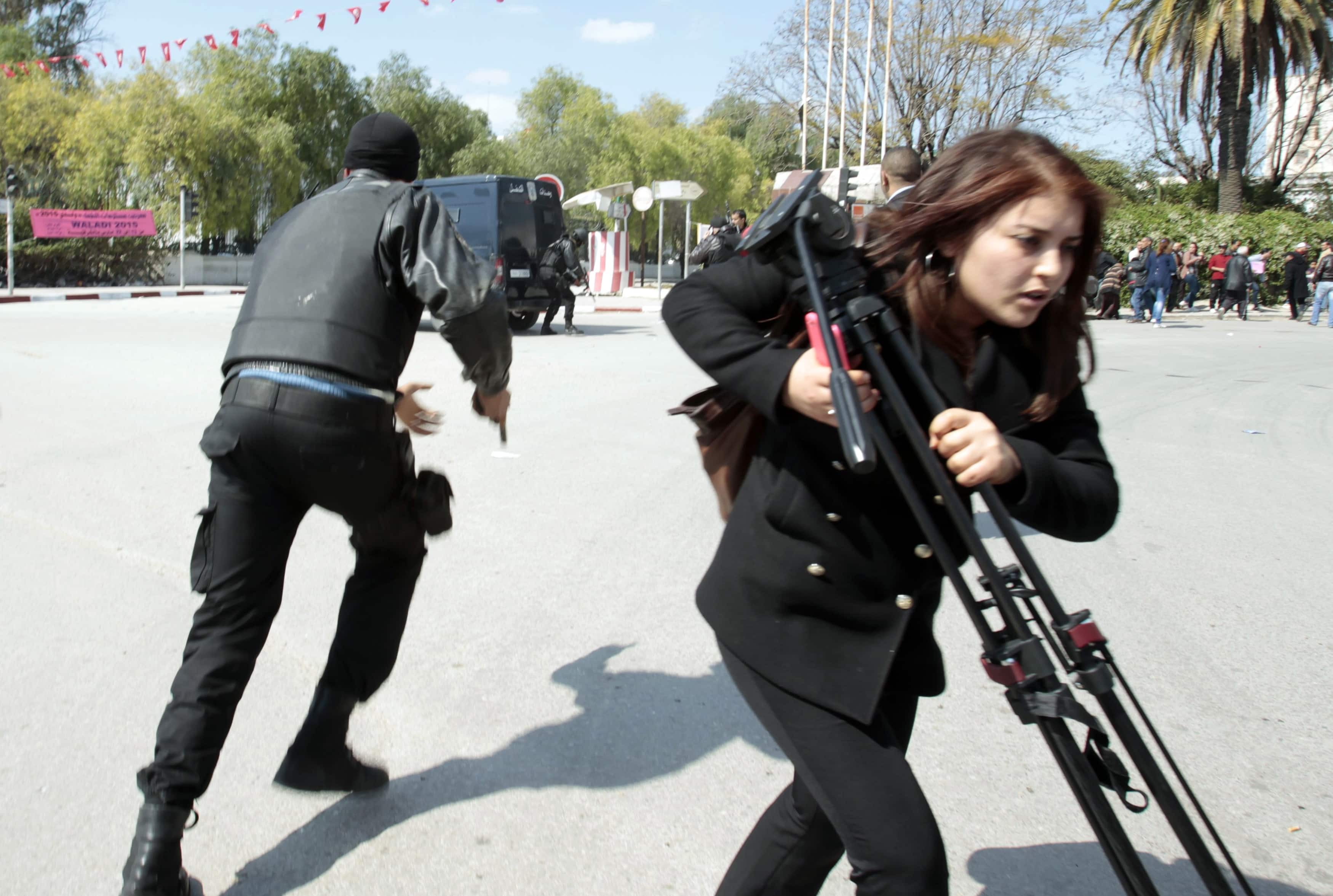 Police officers and a journalist run outside the parliament in Tunis March 18, 2015 after gunmen in military uniforms stormed Tunisia's national museum, REUTERS/ Zoubeir Souissi