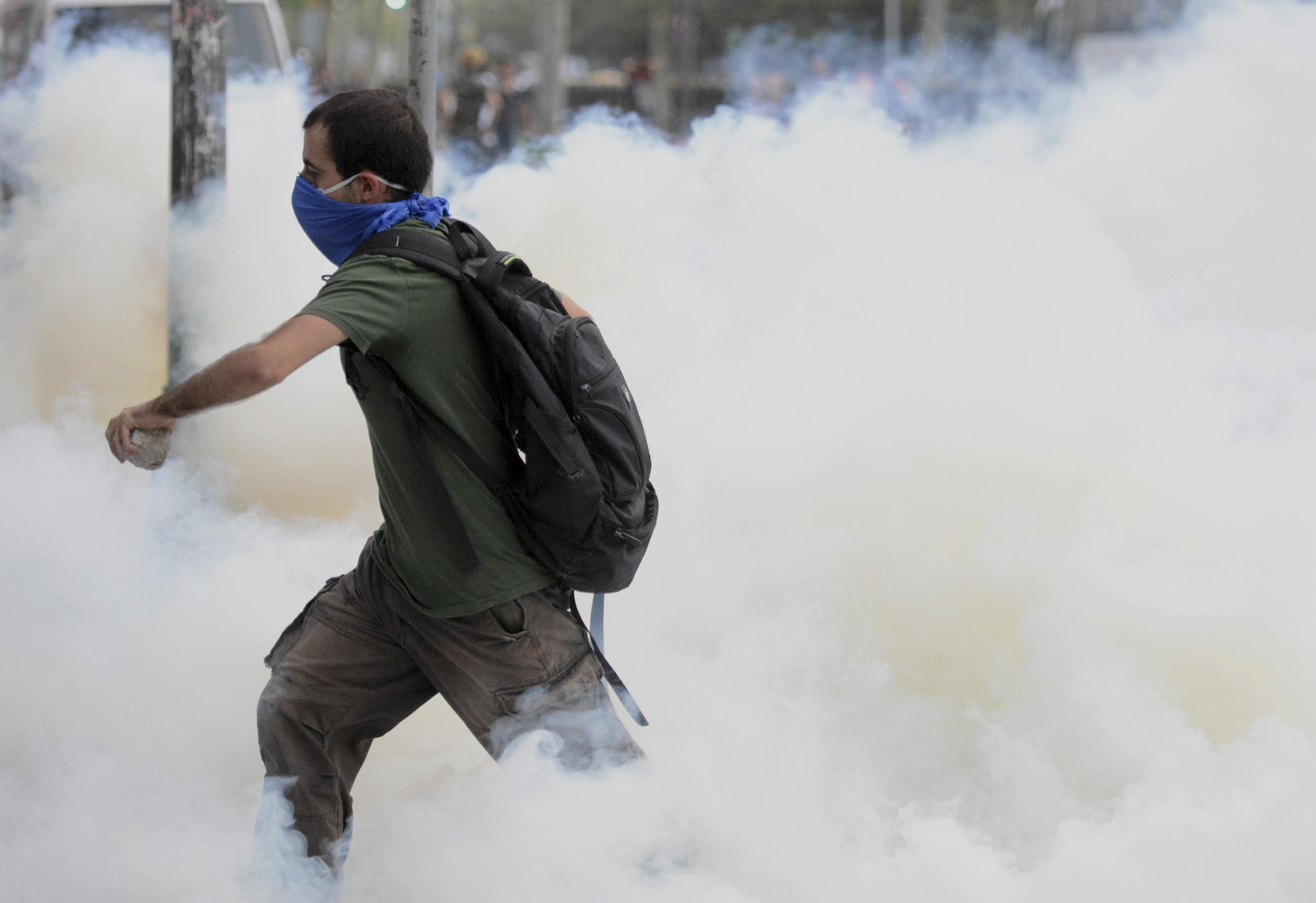 A man runs through tear gas smoke fired by riot police in Istanbul, 31 May 2013. , ASSOCIATED PRESS