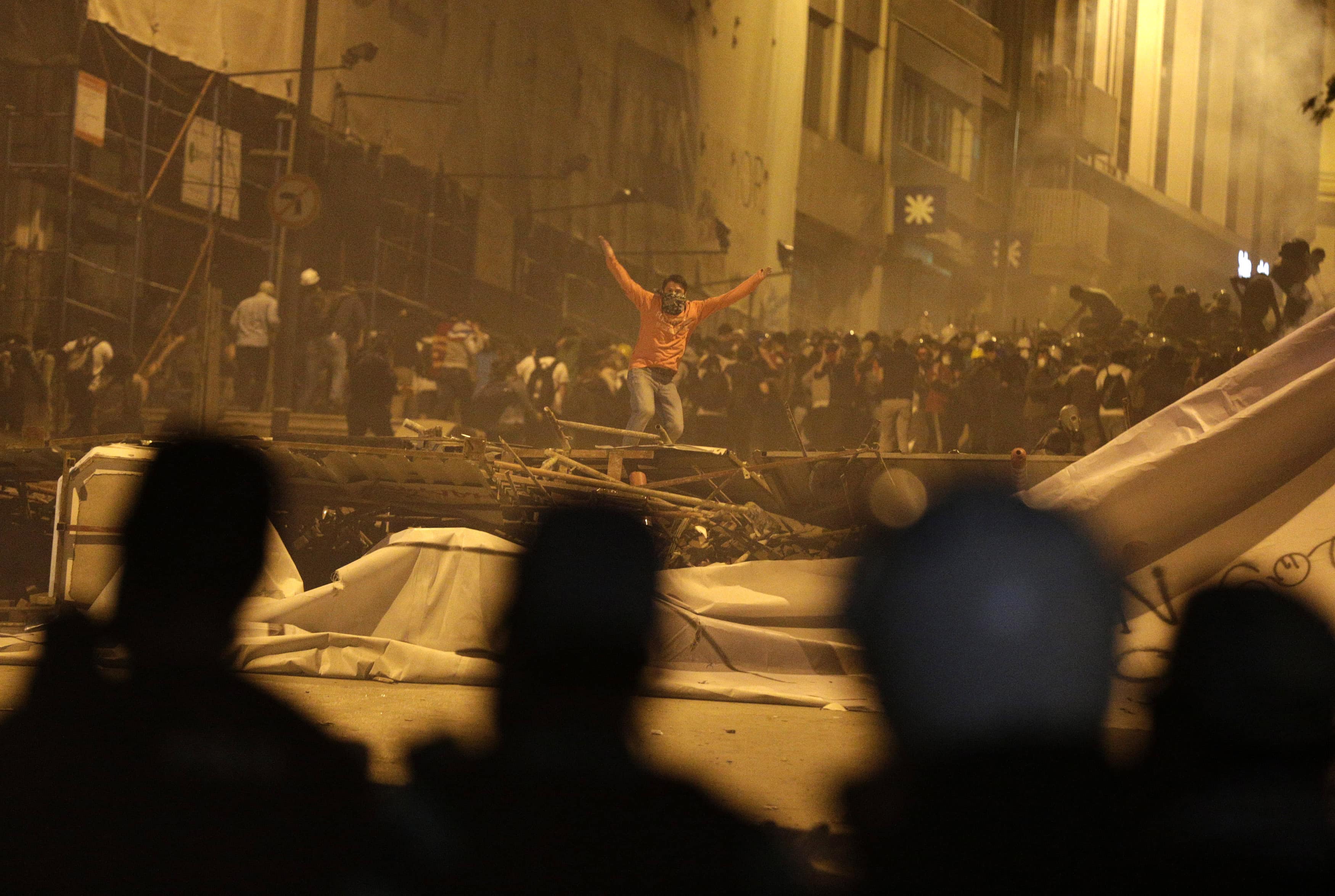 A protester gestures towards riot police after they fired tear gas in front of a barricade in Istanbul, 4 June 2013., REUTERS/Stoyan Nenov