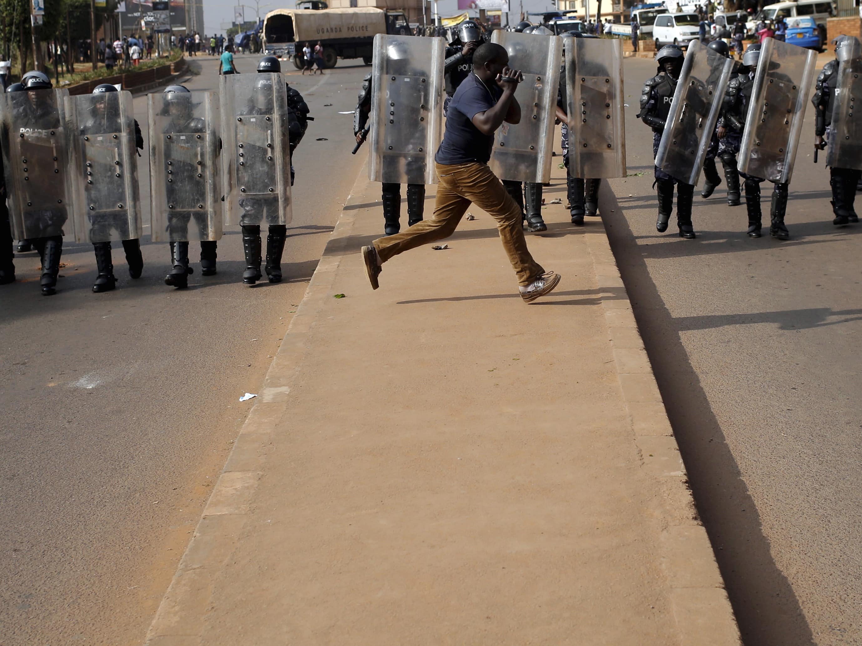 A journalist runs in front of riot police in Kampala, Uganda, 15 February 2016, REUTERS/Goran Tomasevic