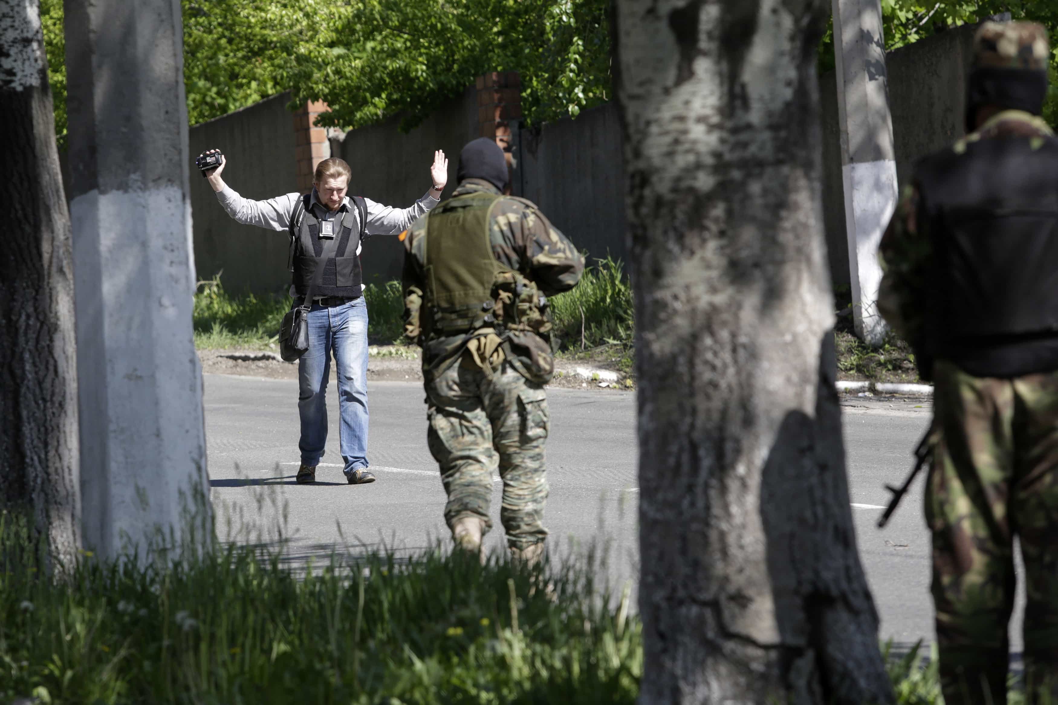 Pro-Russian armed separatists check a journalist at gunpoint in Donetsk May 6, 2014. , REUTERS/Konstantin Chernichkin