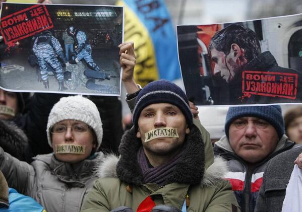 Protesters hold signs that read "they made it legal," and wear tape that says "dictatorship," in Kyiv, 17 January 2014., Civic Sector of Euromaidan/Facebook