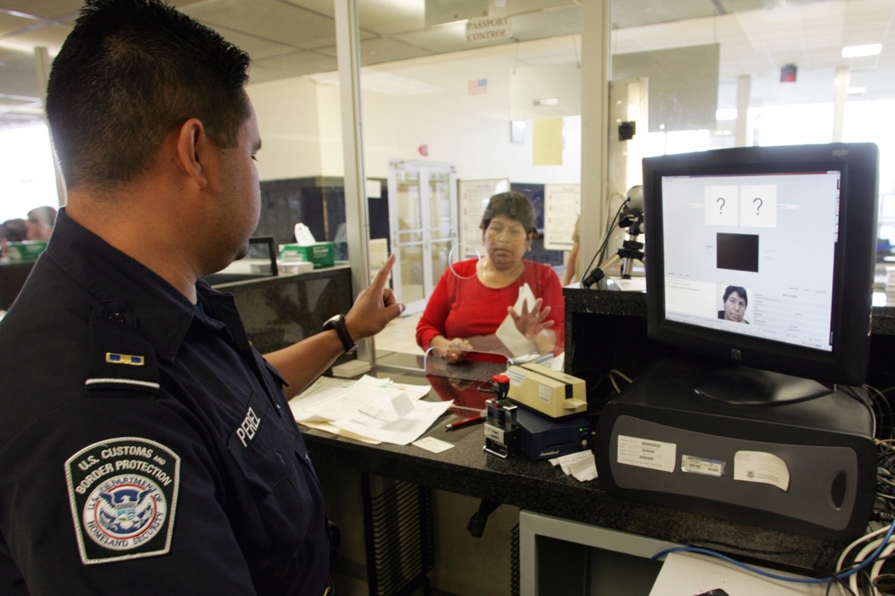 A US Customs officer indicates which finger he wants a woman to press against a scanner connected to his computer, on the US-Mexico border, 5 April 2006, Steven Clevenger/Corbis via Getty Images