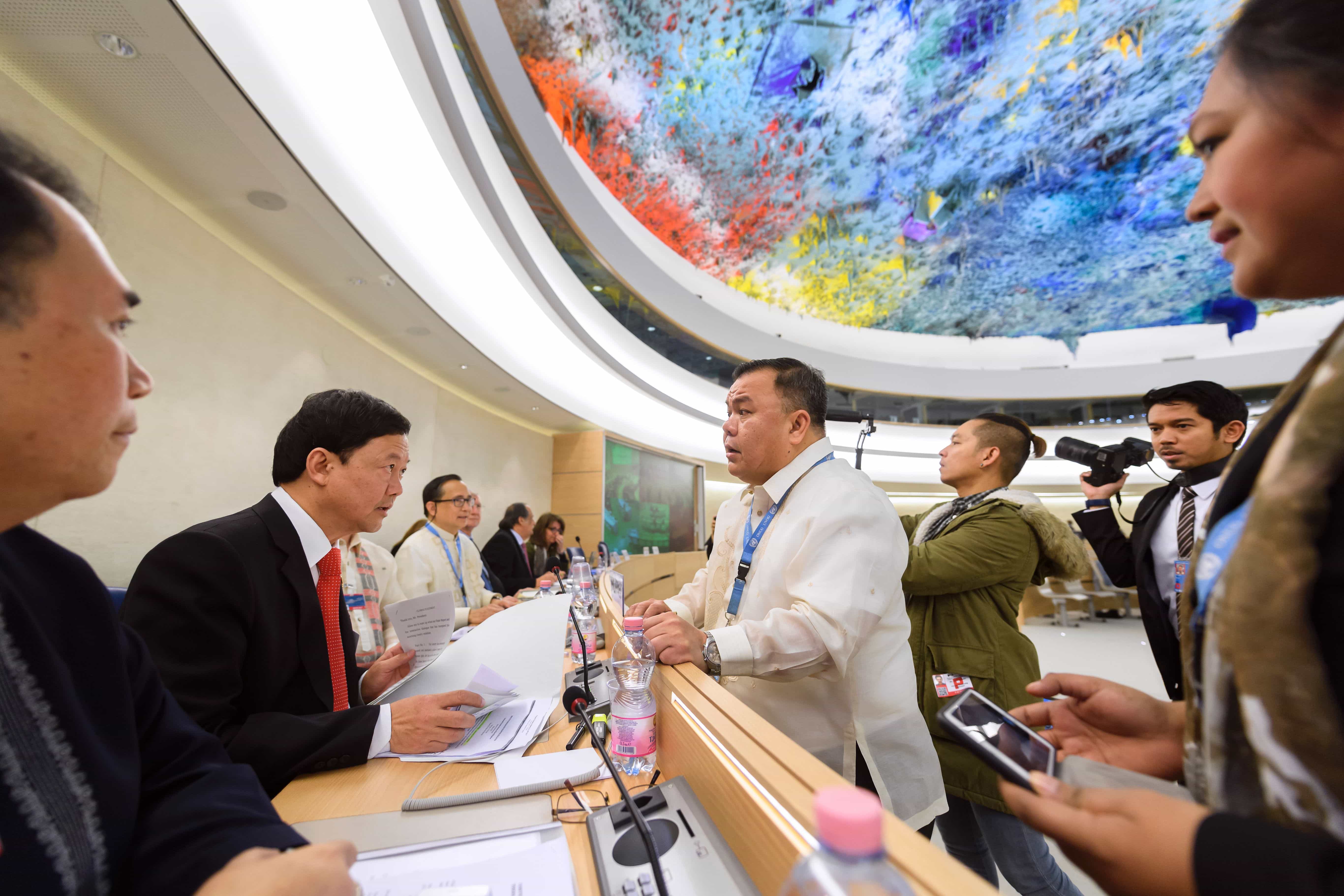 El Jefe de la delegación de Filipinas habla con un hombre antes del comienzo del Examen Periódico Universal de Filipinas por parte de la Oficina del Alto Comisionado de las Naciones Unidas para los Derechos Humanos, el 8 de mayo de 2017, FABRICE COFFRINI/AFP/Getty Images