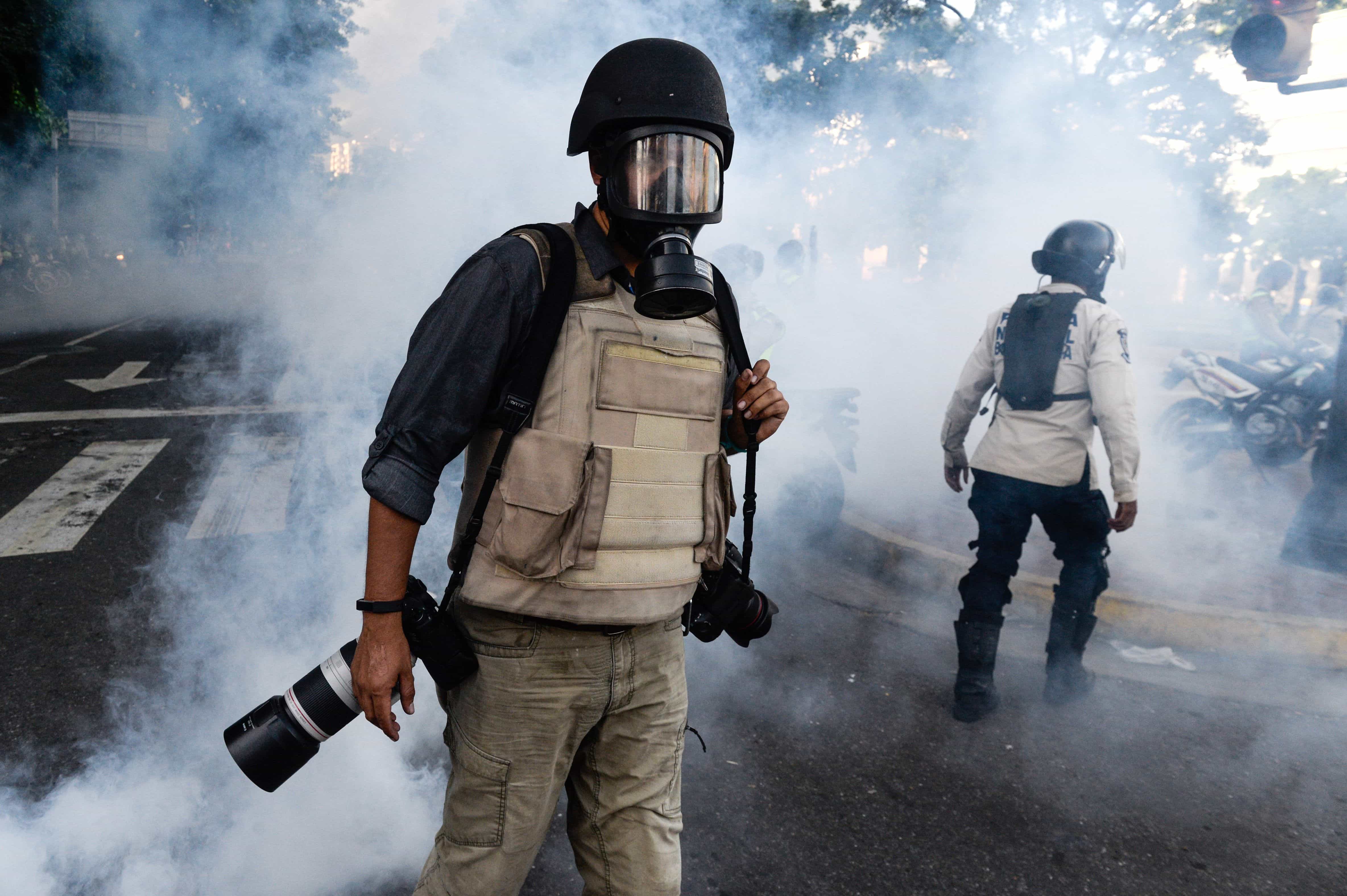 A photojournalist wades through a cloud of tear gas as opposition activists demonstrate against the government of Venezuelan President Nicolas Maduro in Caracas, 26 June 2017, FEDERICO PARRA/AFP/Getty Images
