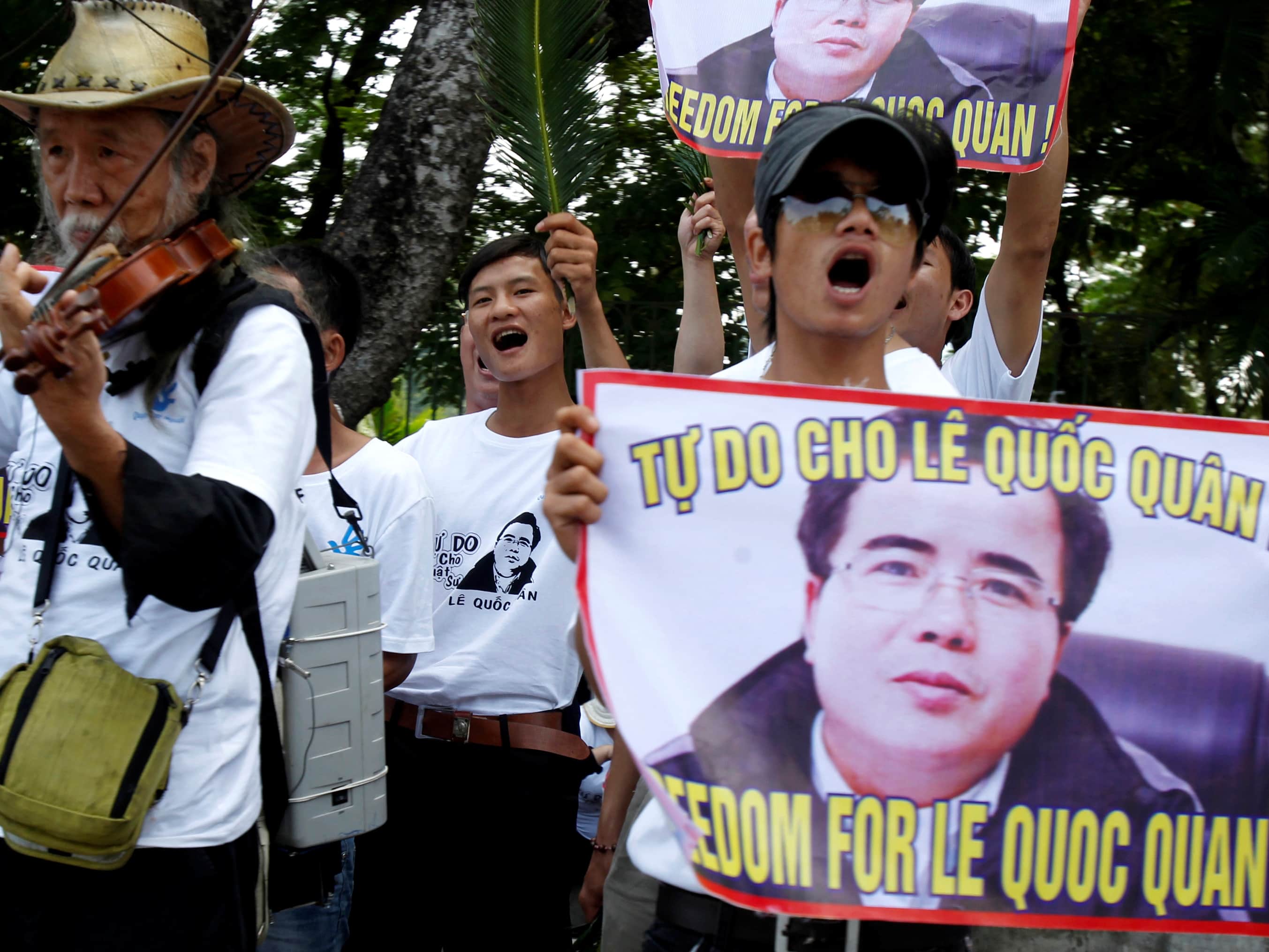 Friends and supporters of lawyer Le Quoc Quan hold posters bearing his image as they protest for his freedom outside a court in Hanoi, 2 October 2013, REUTERS/Kham
