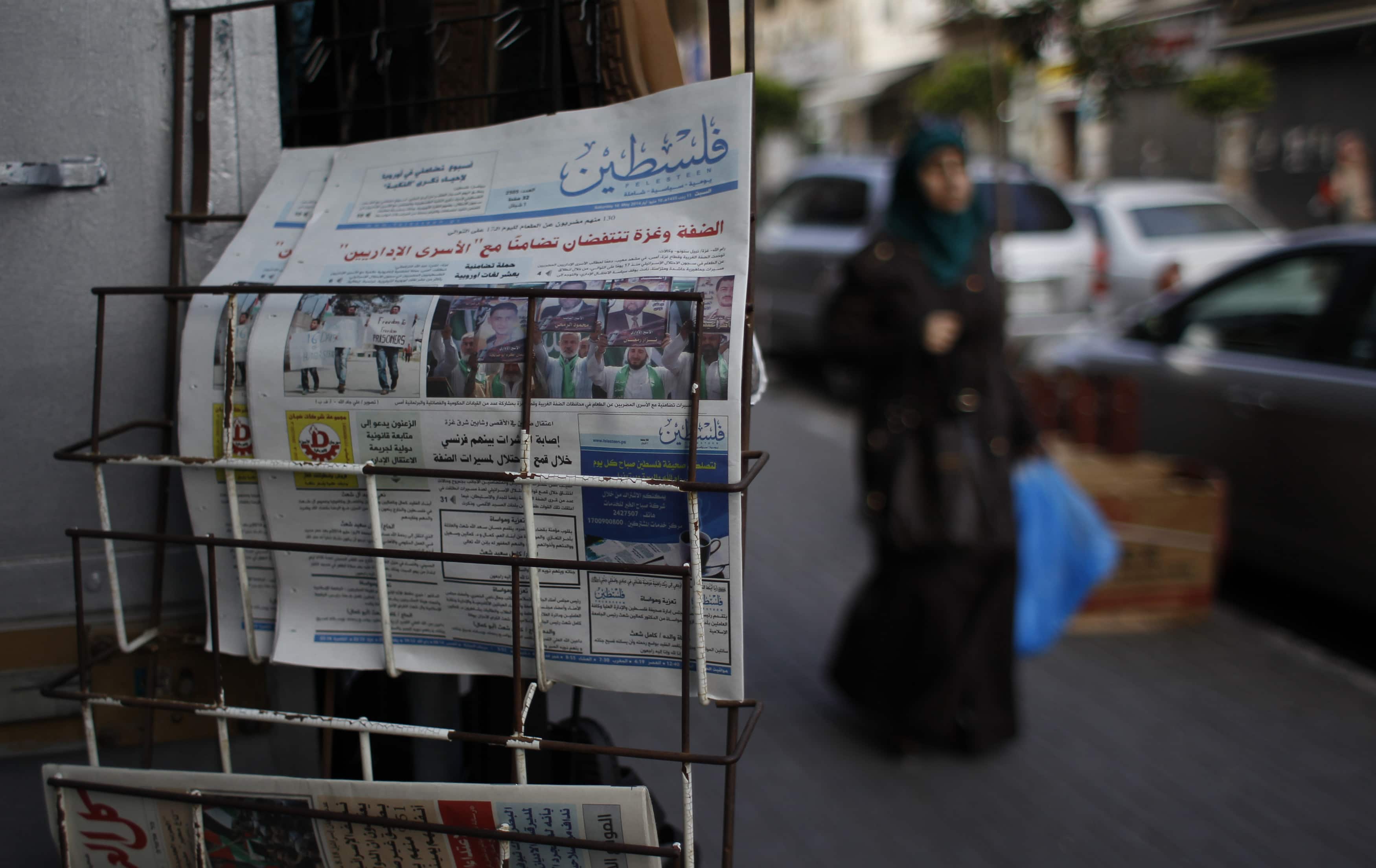 A Palestinian woman walks past copies of a pro-Hamas newspaper outside a shop in the West Bank, REUTERS/Mohamad Torokman