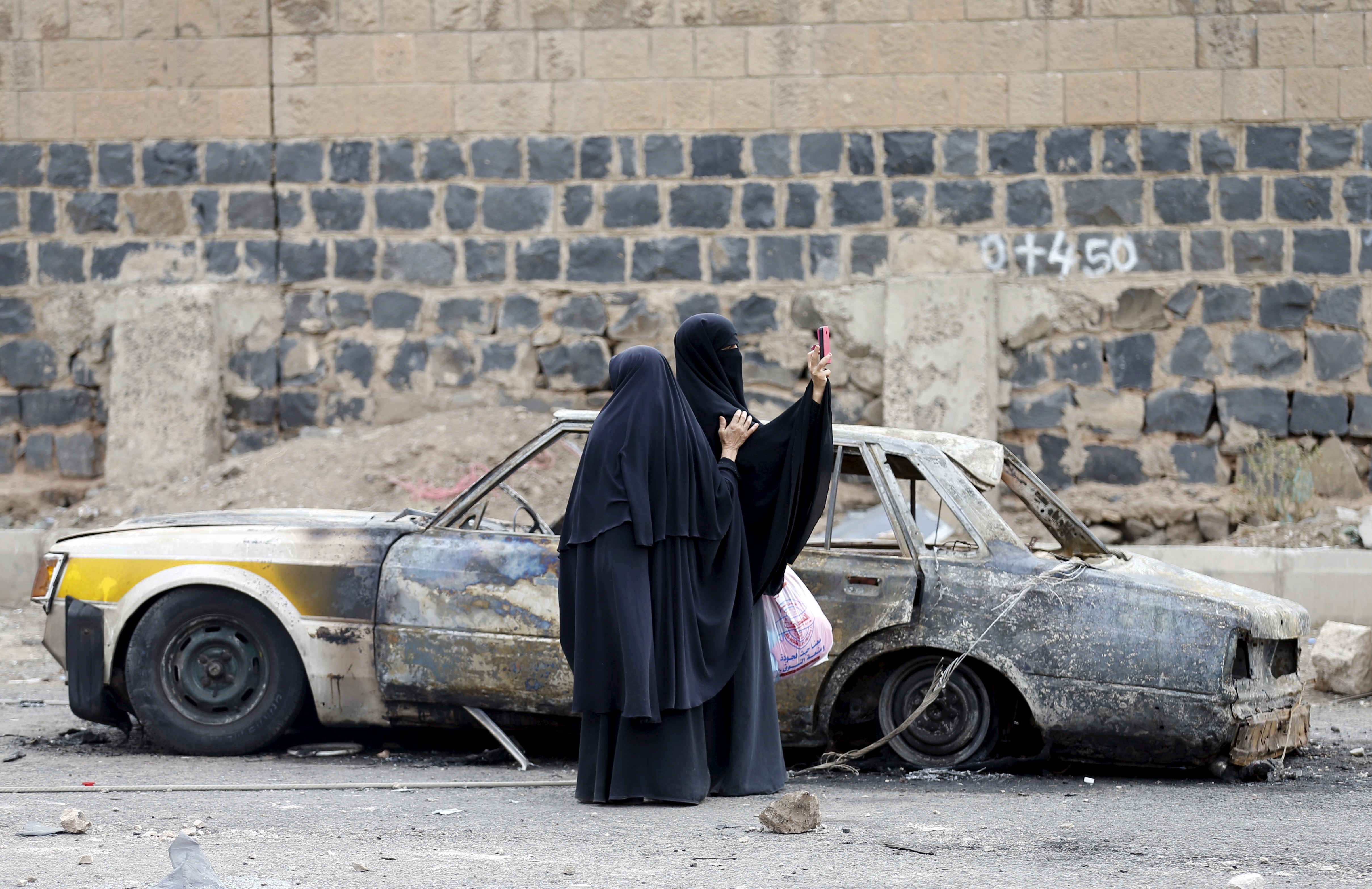 A woman takes photos with her mobile phone at the site of a Saudi-led air strike in Yemen's capital Sanaa July 14, 2015, REUTERS/Khaled Abdullah