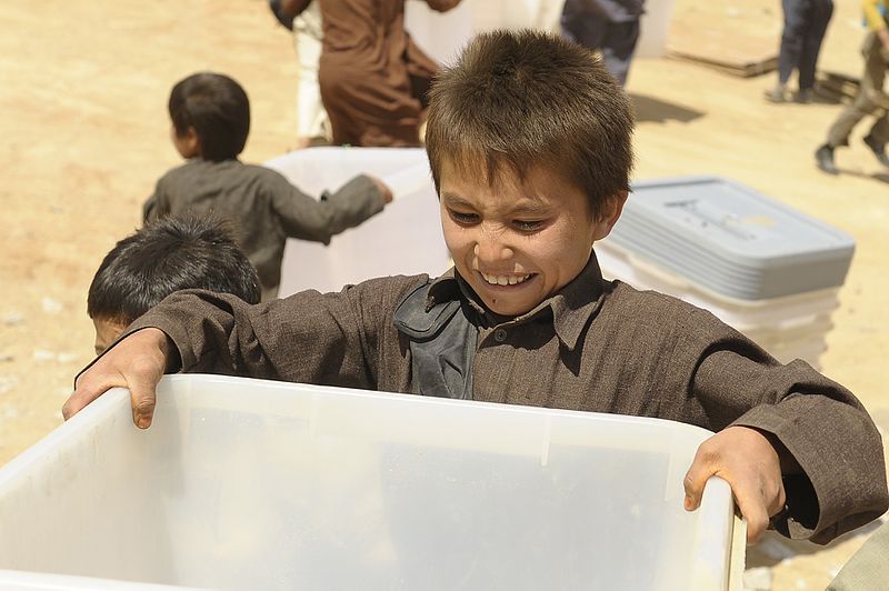 An Afghan boy helps unload ballot materials from an Mi-17 helicopter in Jaghuri, Afghanistan, 16 September 2010, Staff Sgt. Joseph Swafford/Public Domain
